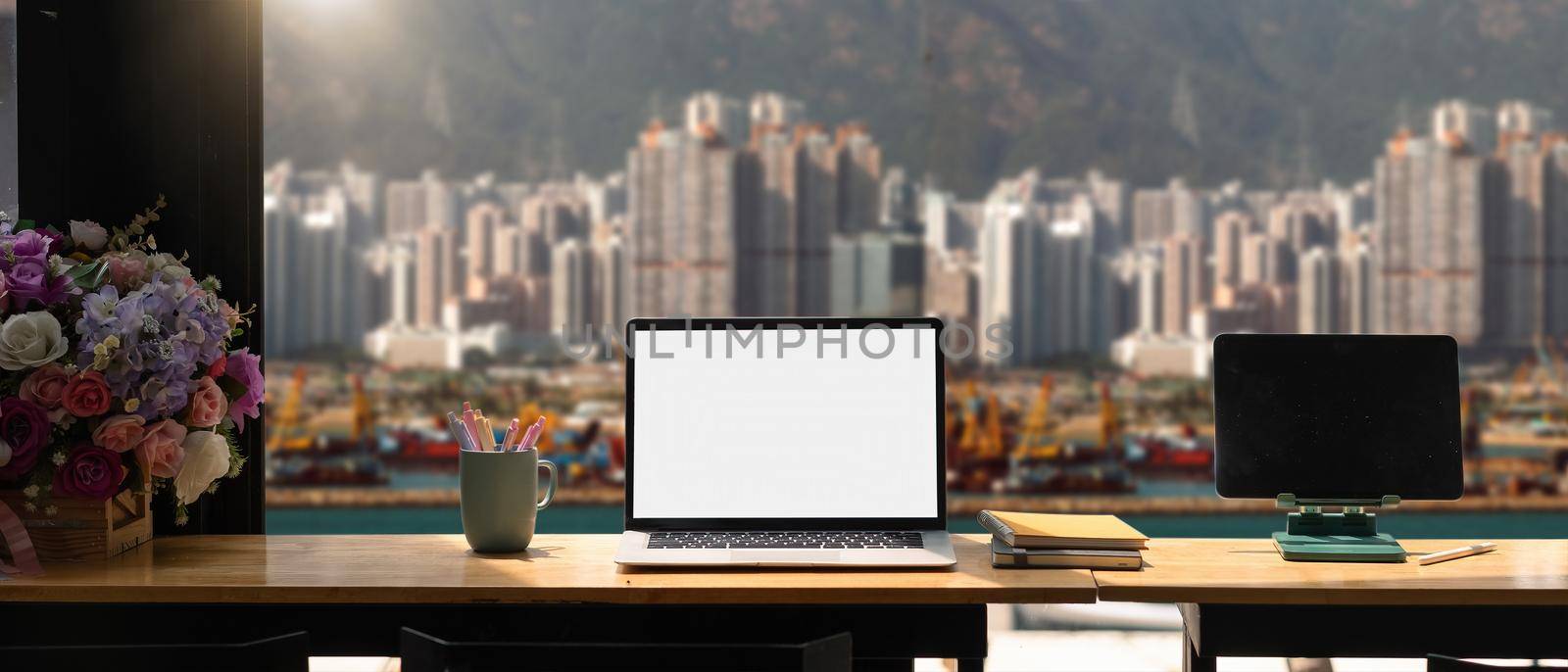 Mockup laptop computer with blank white screen on workplace, cargo port and building background by nateemee