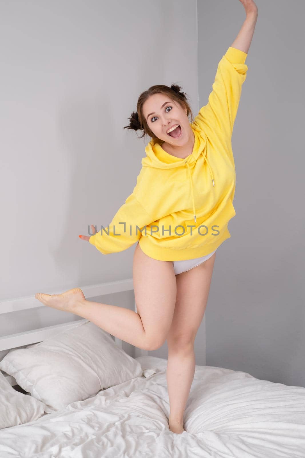 happy positive brunette in yellow hoodie in bright room. happy people. millennial generation. fashionable teenager. trendy colours by oliavesna