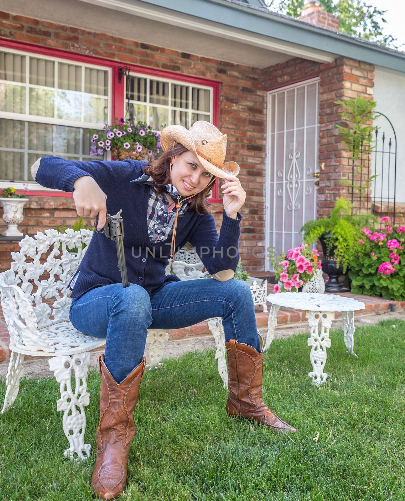 Country style portrait of a beautiful brunette young woman with a gun and cowboy hat
