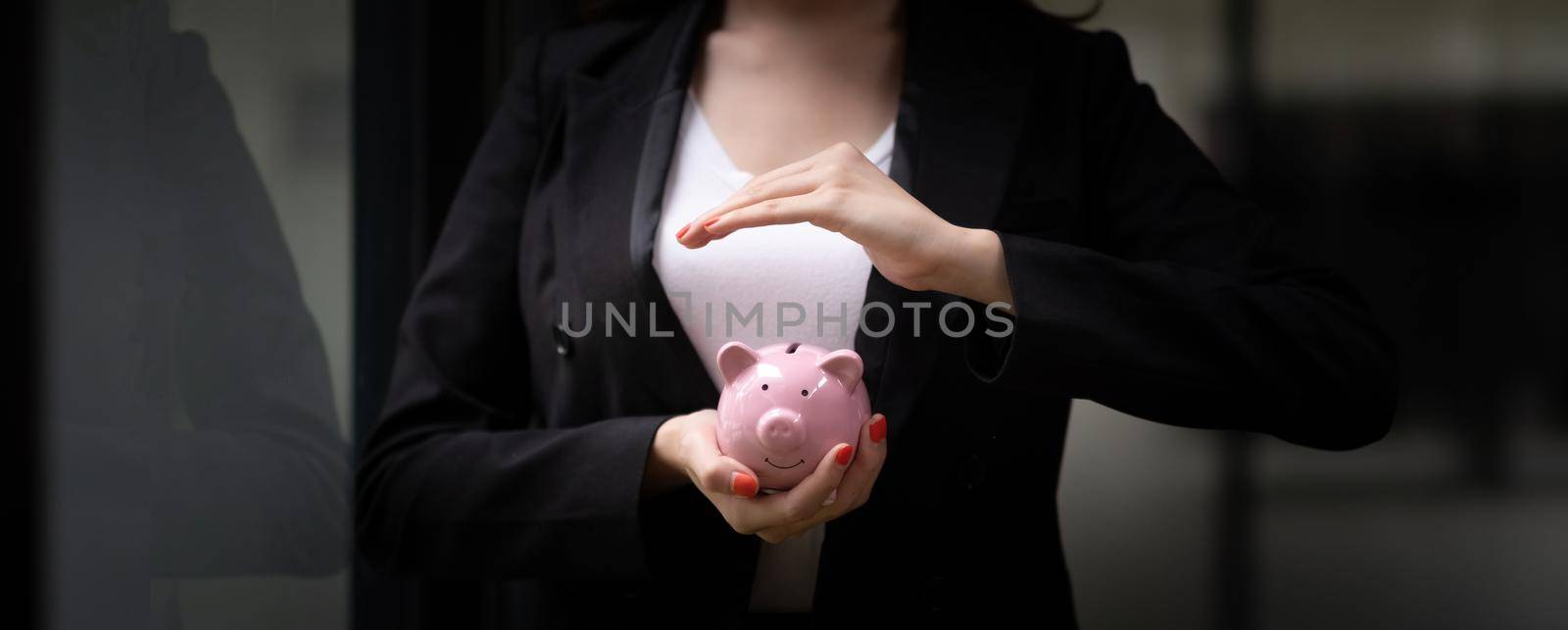 Panoramic image, Business woman hand holding and cover piggy bank. Save money and financial investment concept.