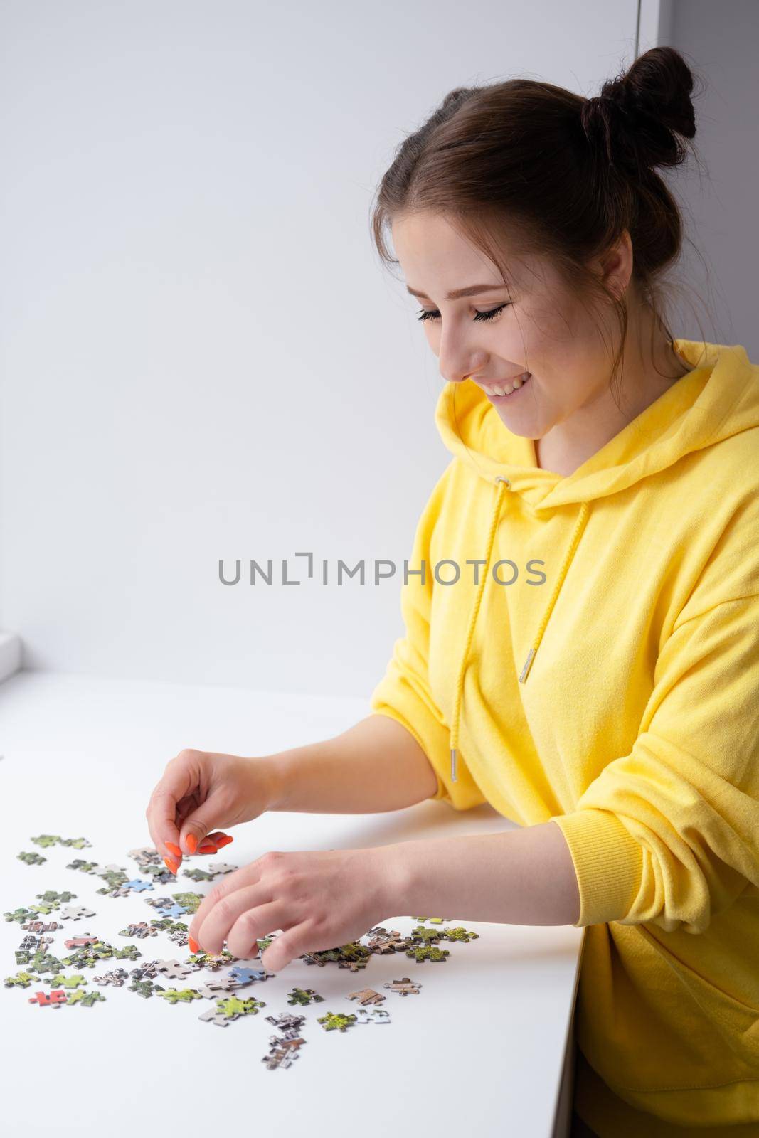 Young Woman trying to match pieces of a Jigsaw Puzzle Game. Playing board game. by oliavesna