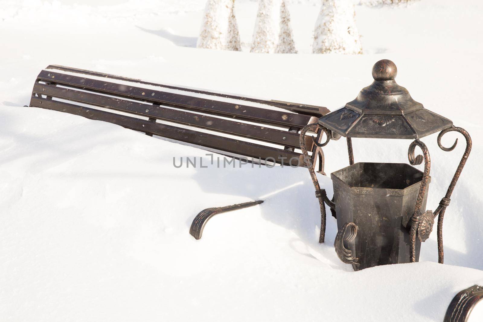 Wooden bench covered with snow in a winter park