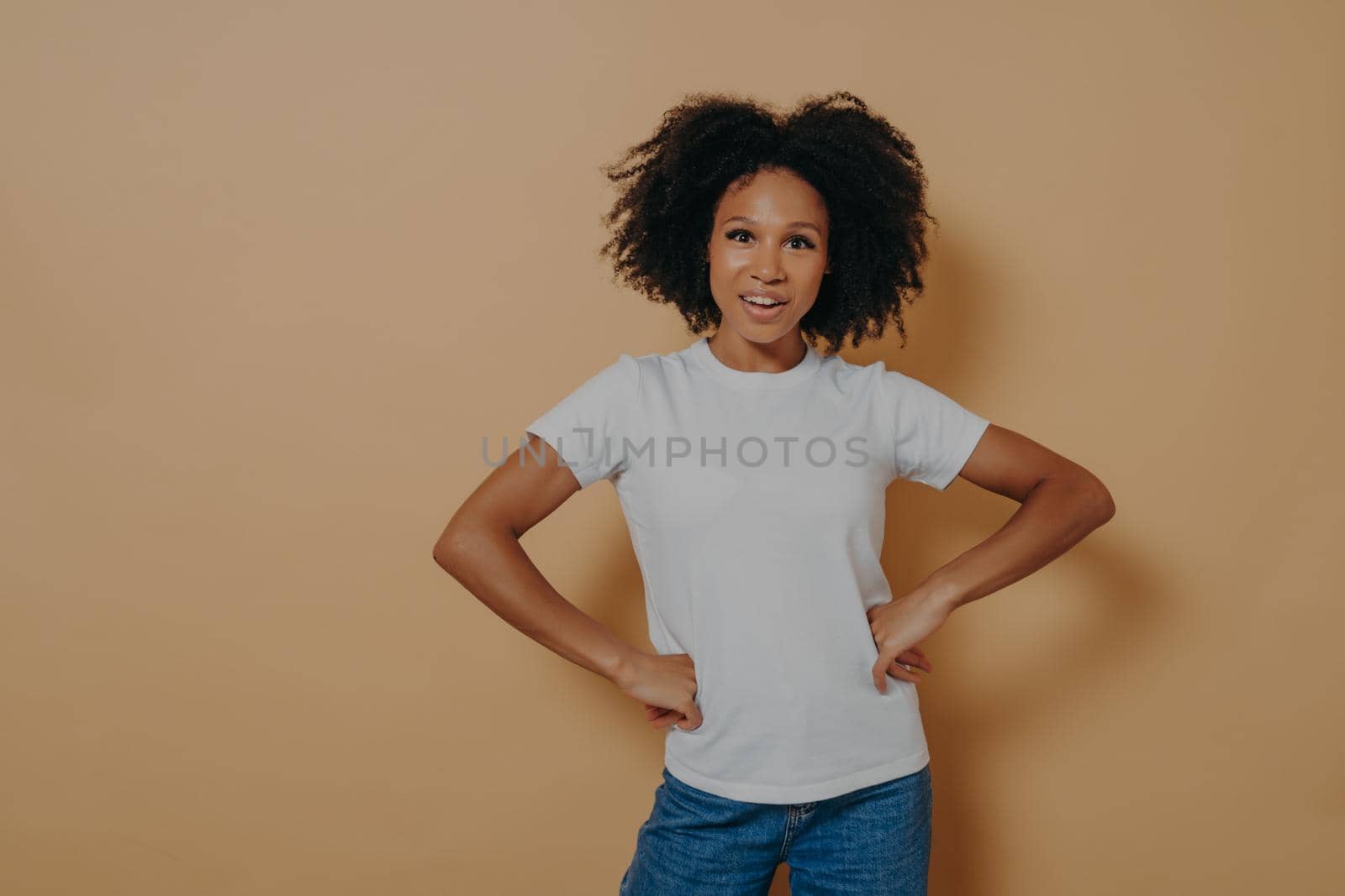 Beautiful confident african american female wearing casual stylish clothes keeping hands on hips by vkstock