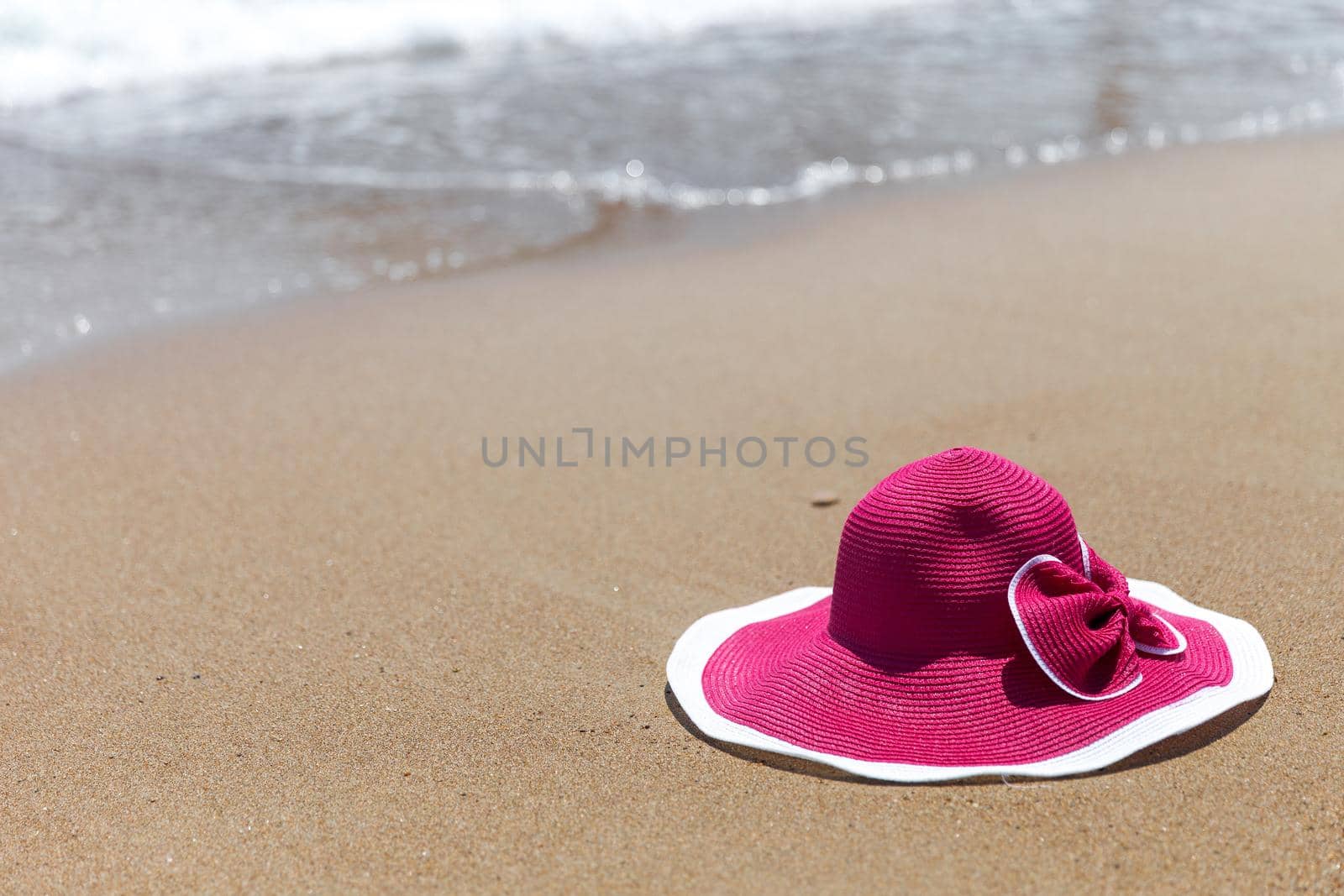 Pink hat on the sandy beach of the sea