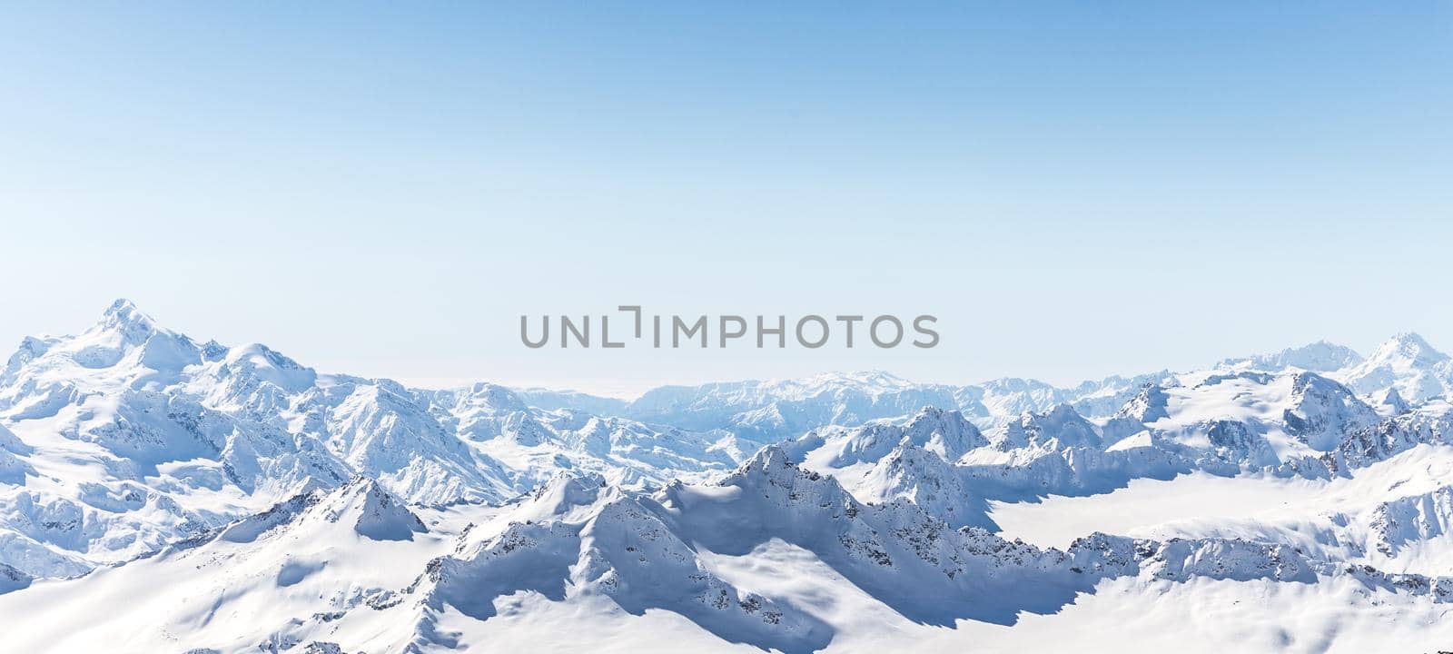 White snowy winter Caucasus mountains at sunny day. Panorama view from ski slope Elbrus, Russia with sky background