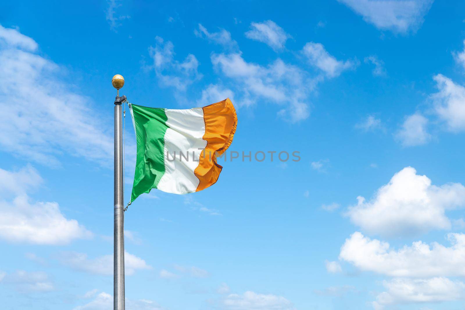 Irish tricolour flying in full sunshine against sky