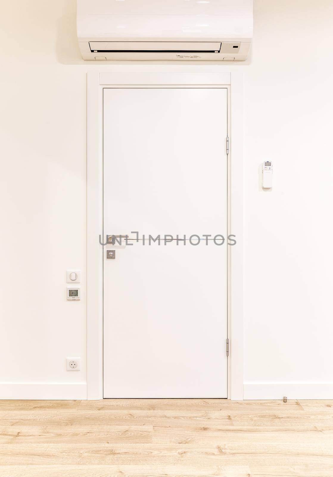 White door in modern home with air conditioner and wooden floor