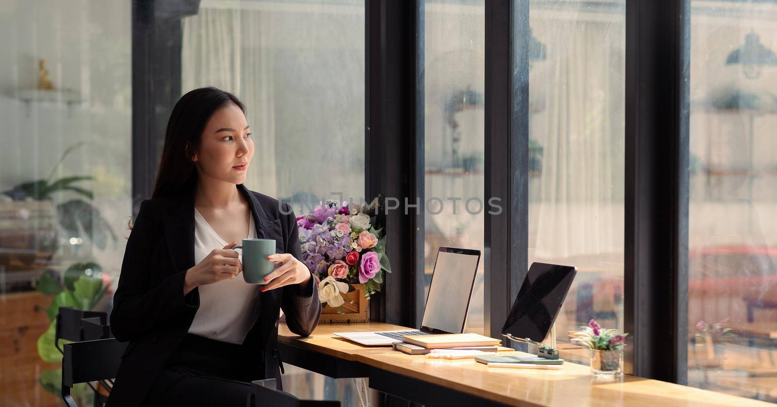 beautiful freelancer working on laptop with coffee cup in home office. portrait asian woman working