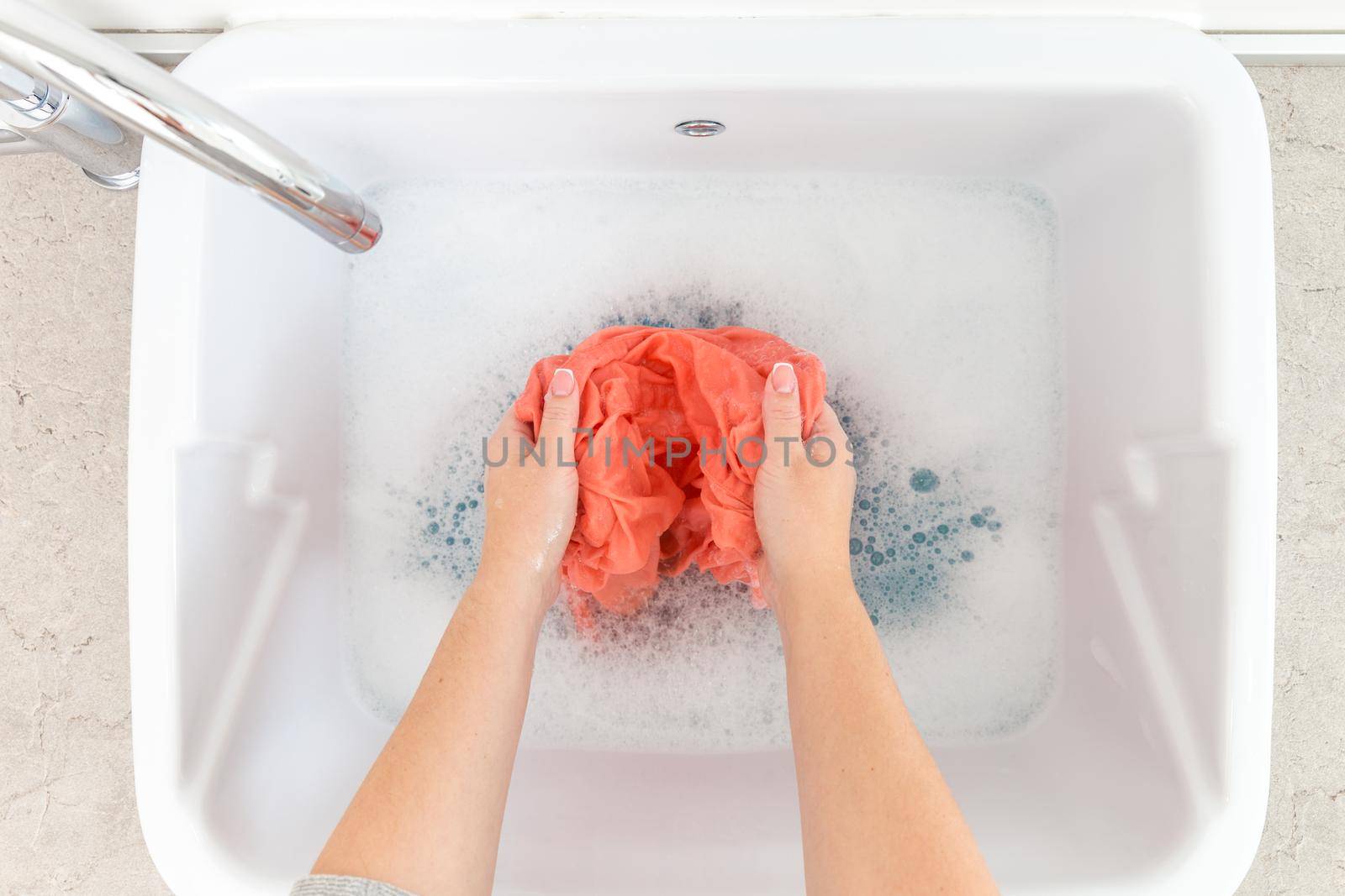 Female hands washing clothes in sink in laundry room