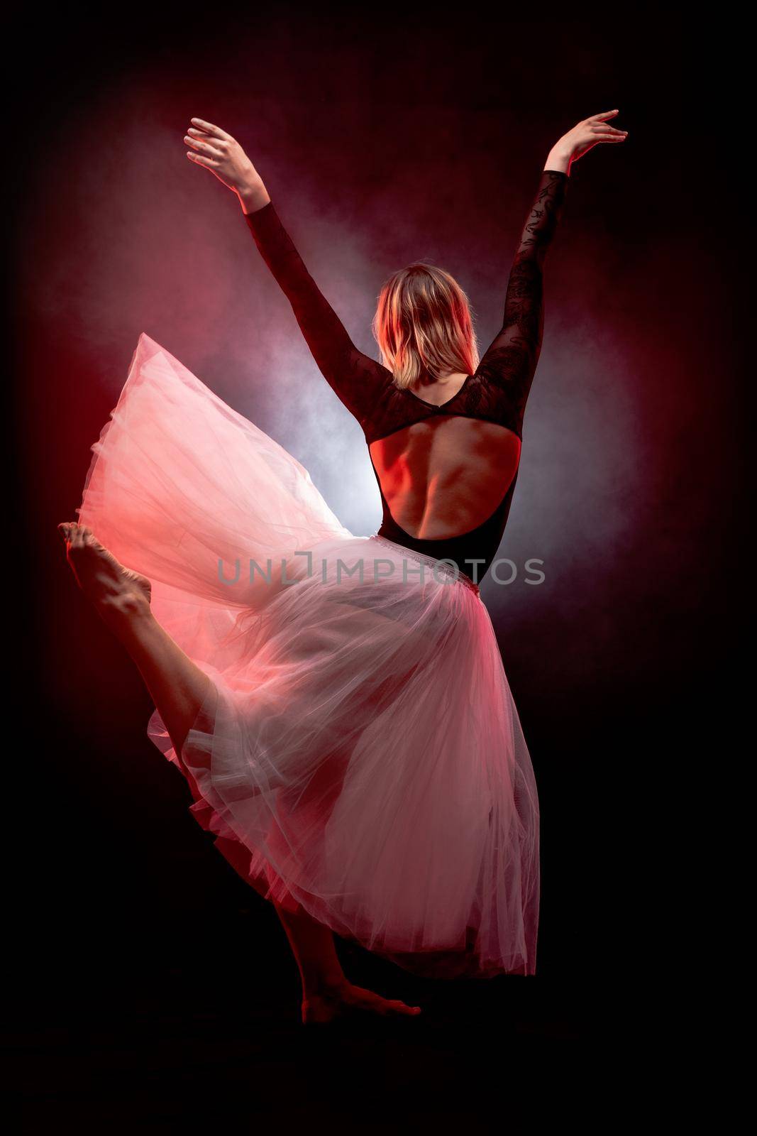 ballerina with a white dress and black top posing on red smoke background.