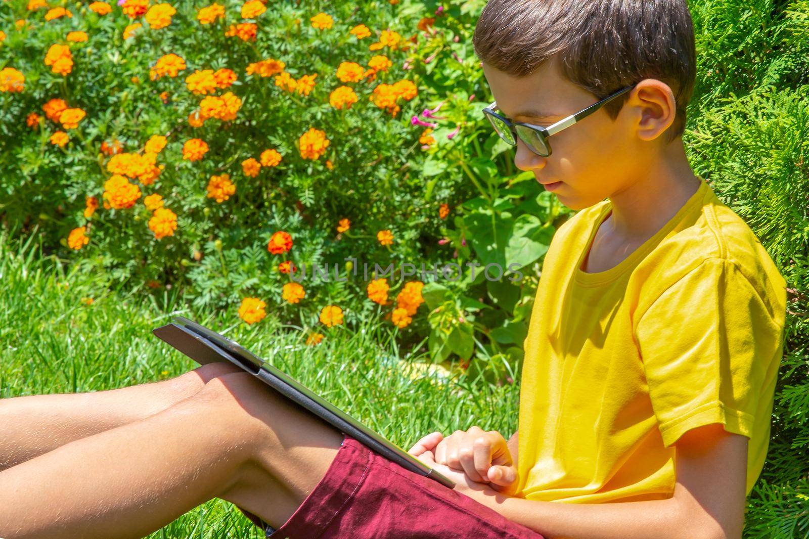 Boy with tablet PC on green grass lawn