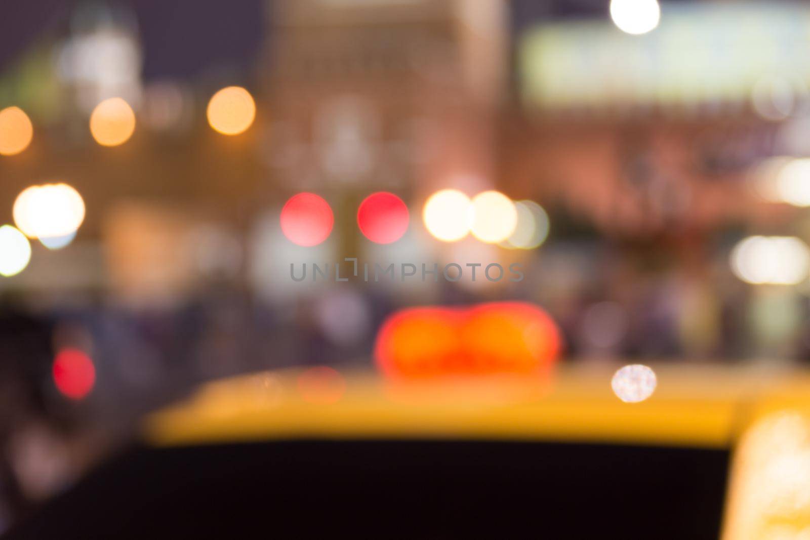 Busy city life blurred with taxi in foreground and street lights illuminating scene