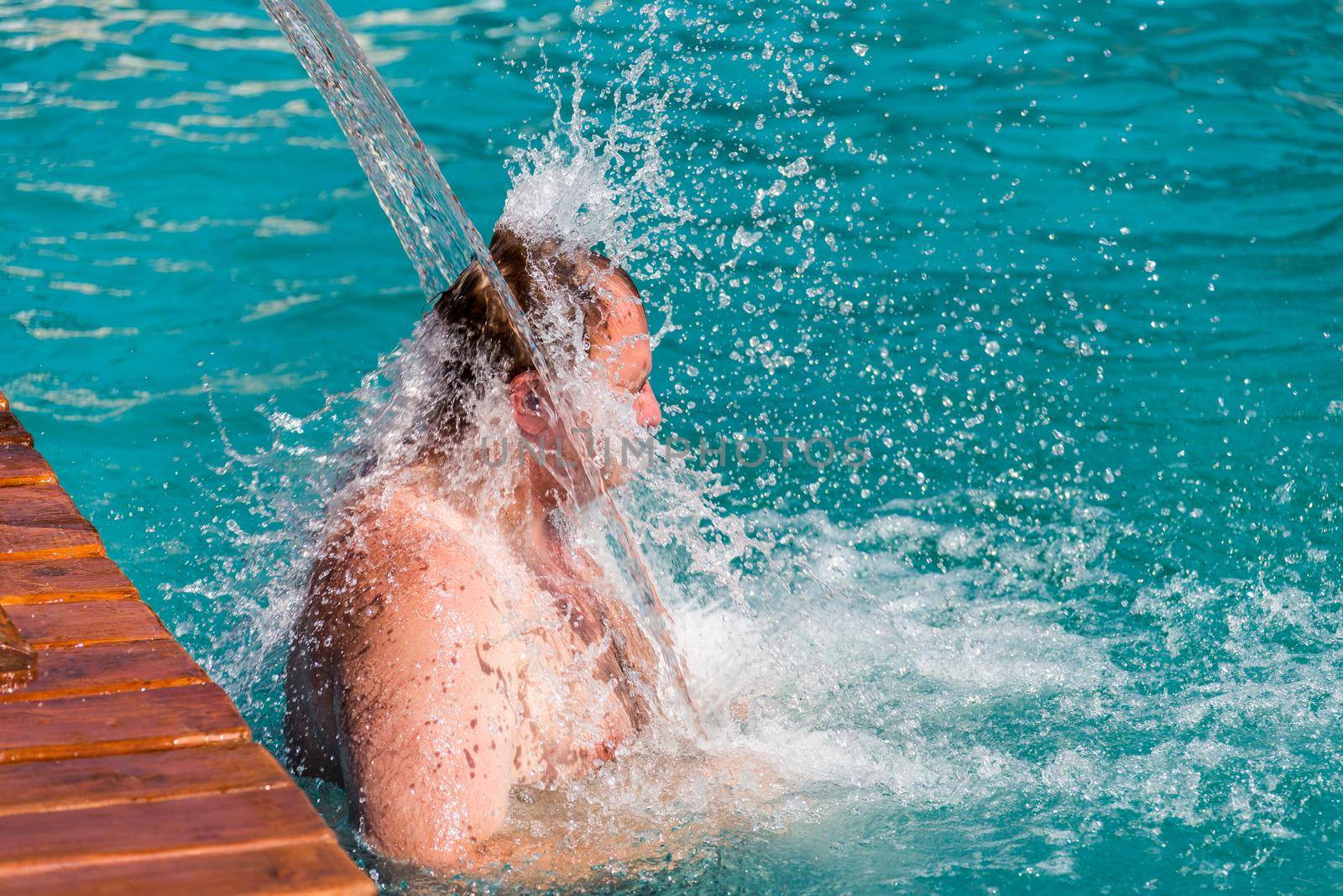 Stream of water splash on Man head in swimming pool