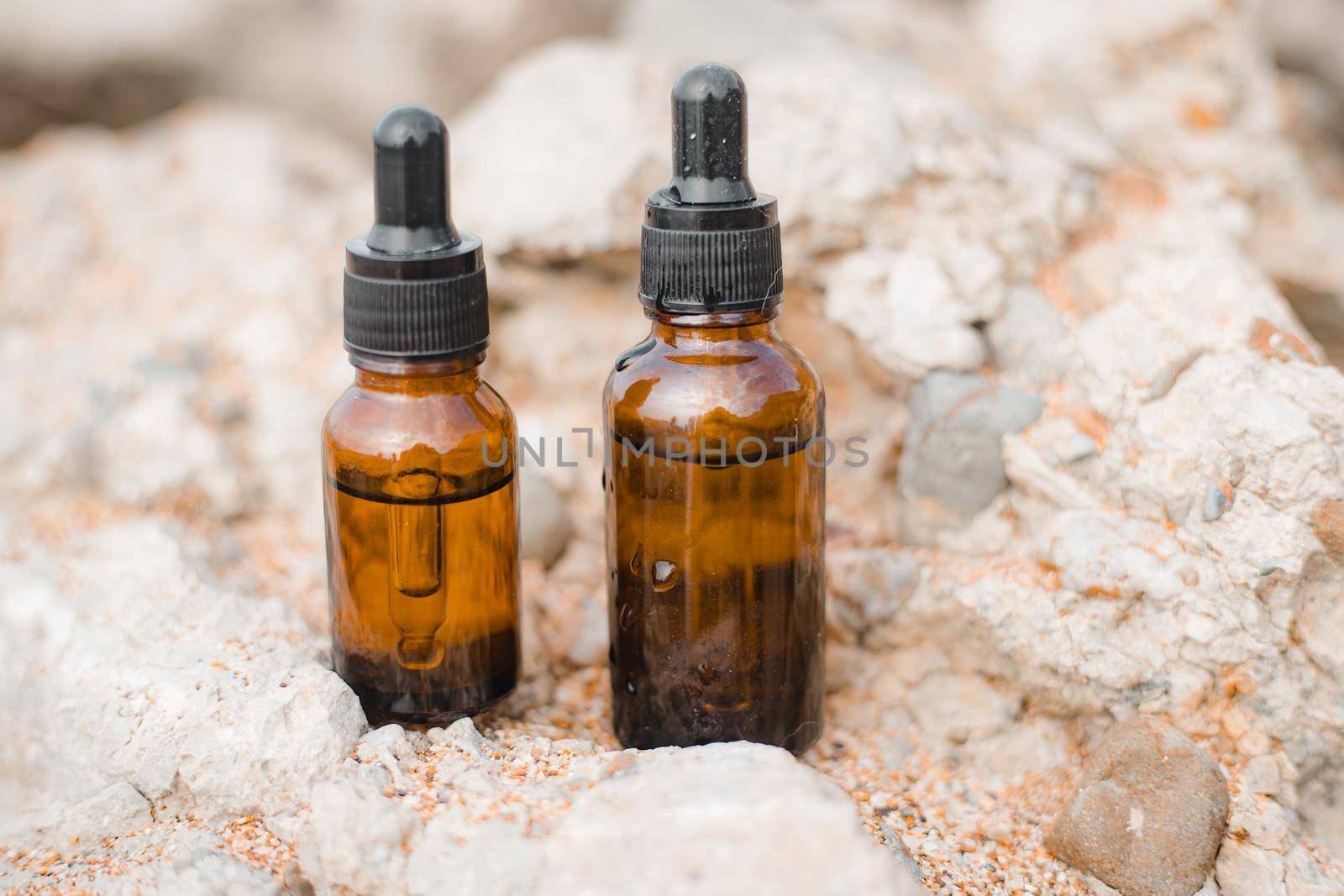 A bottle of cosmetic oil on a background of stones . Cosmetic oil. Cosmetology. Stones. An oil based on algae. Copy Space