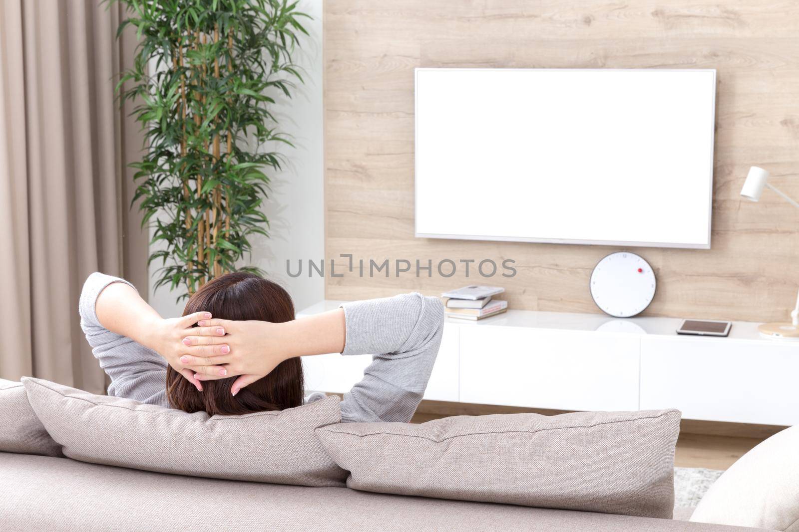 Young woman watching TV in the living room. white screen with copy space