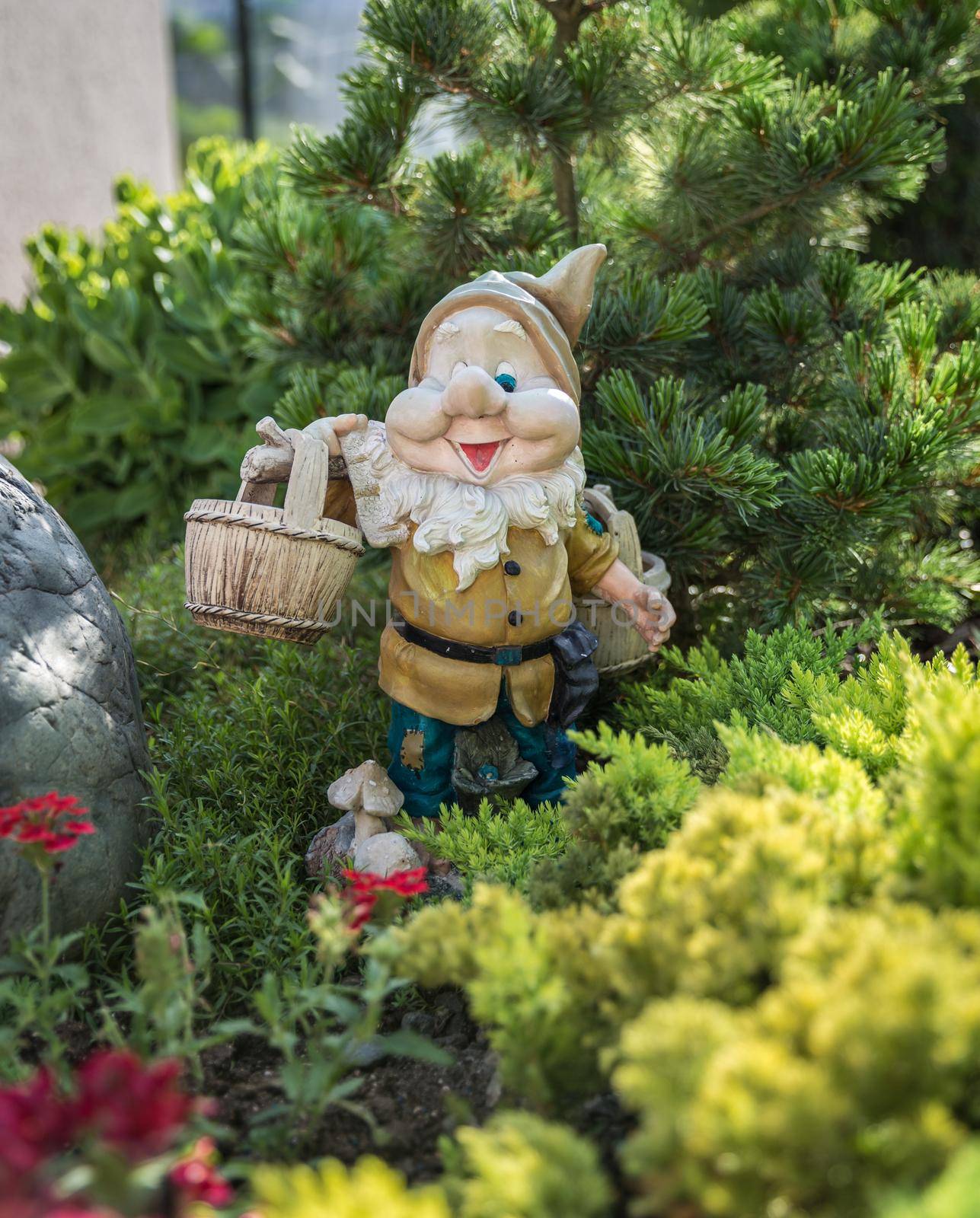Funny garden dwarf standing among nice flowers