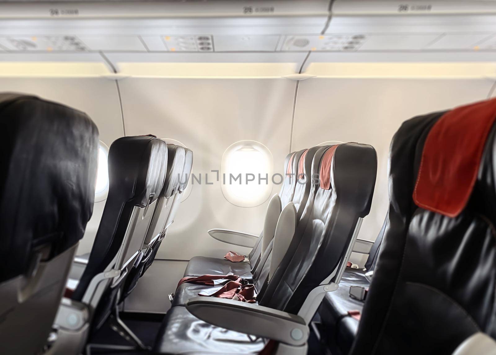 sunlight rays entering through the porthole of a commercial airliner. Interior of an airplane passenger cabin with empty seats. Traveling and transportation