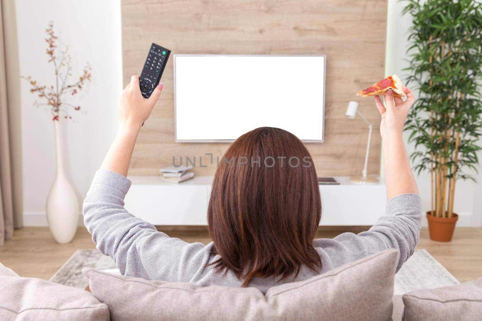 Single woman eating pizza and watching tv by Mariakray
