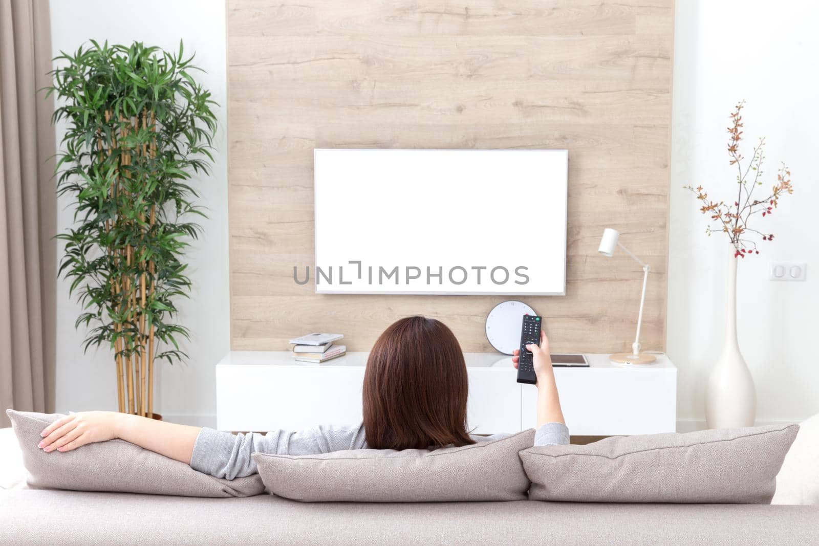 Young woman watching TV in the room. white empty screen for design by Mariakray