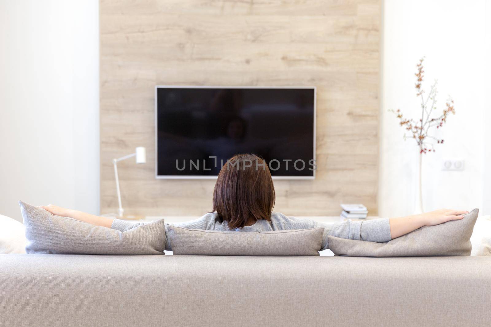 Young woman watching TV in the living room. black screen with copy space