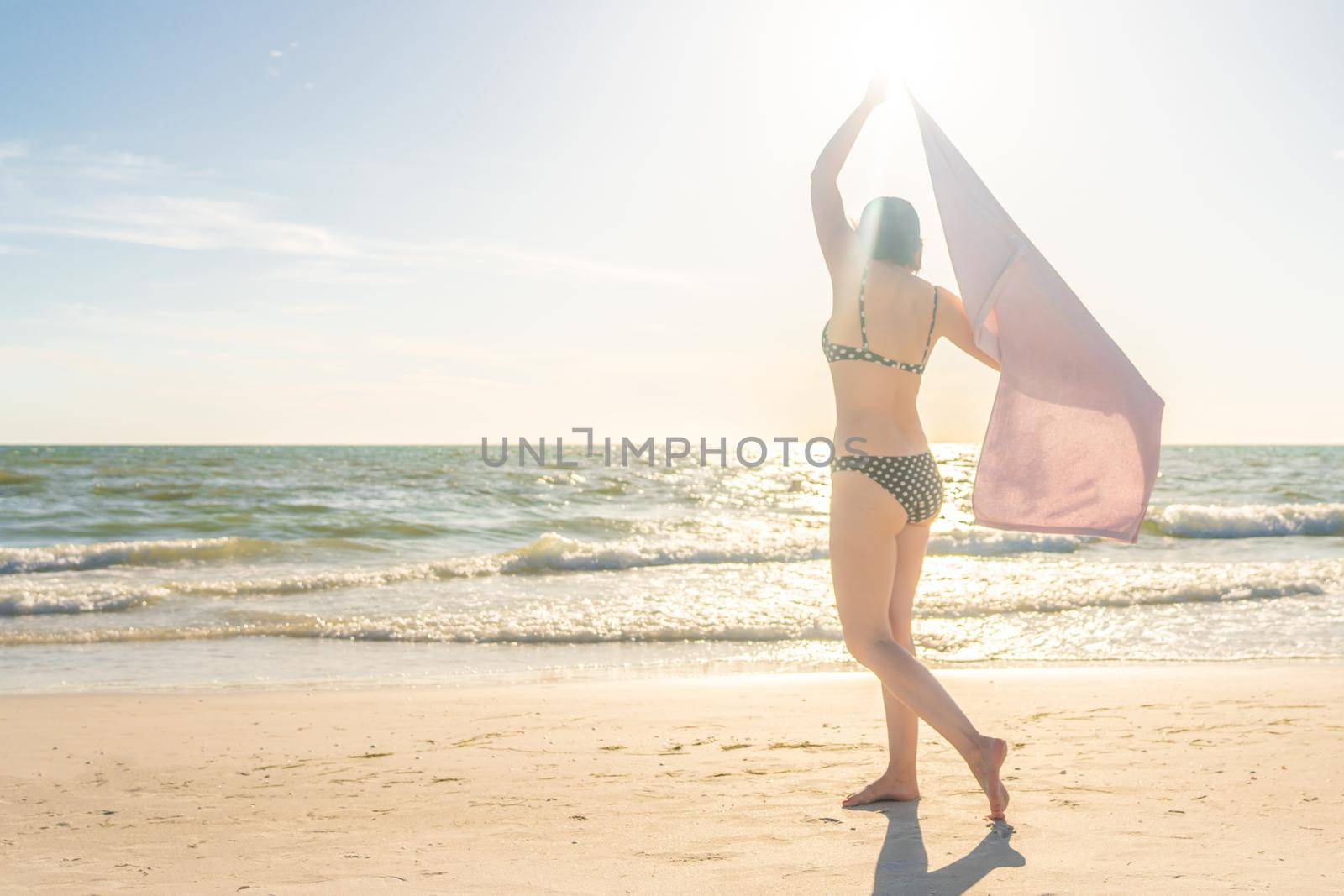 Woman standing with towel on the beach with ocean