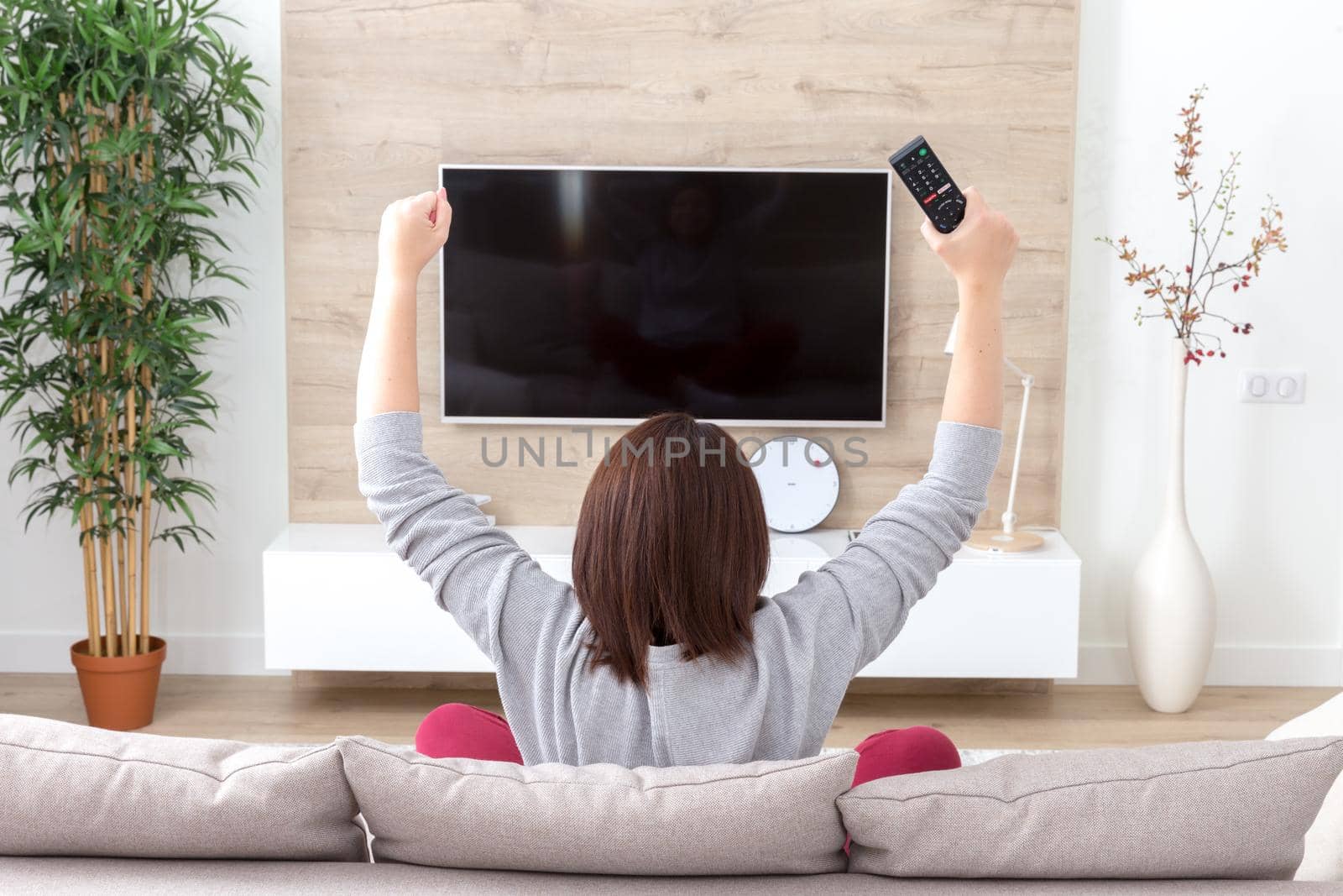 young happy woman watching excited television football sport match or TV contest by Mariakray