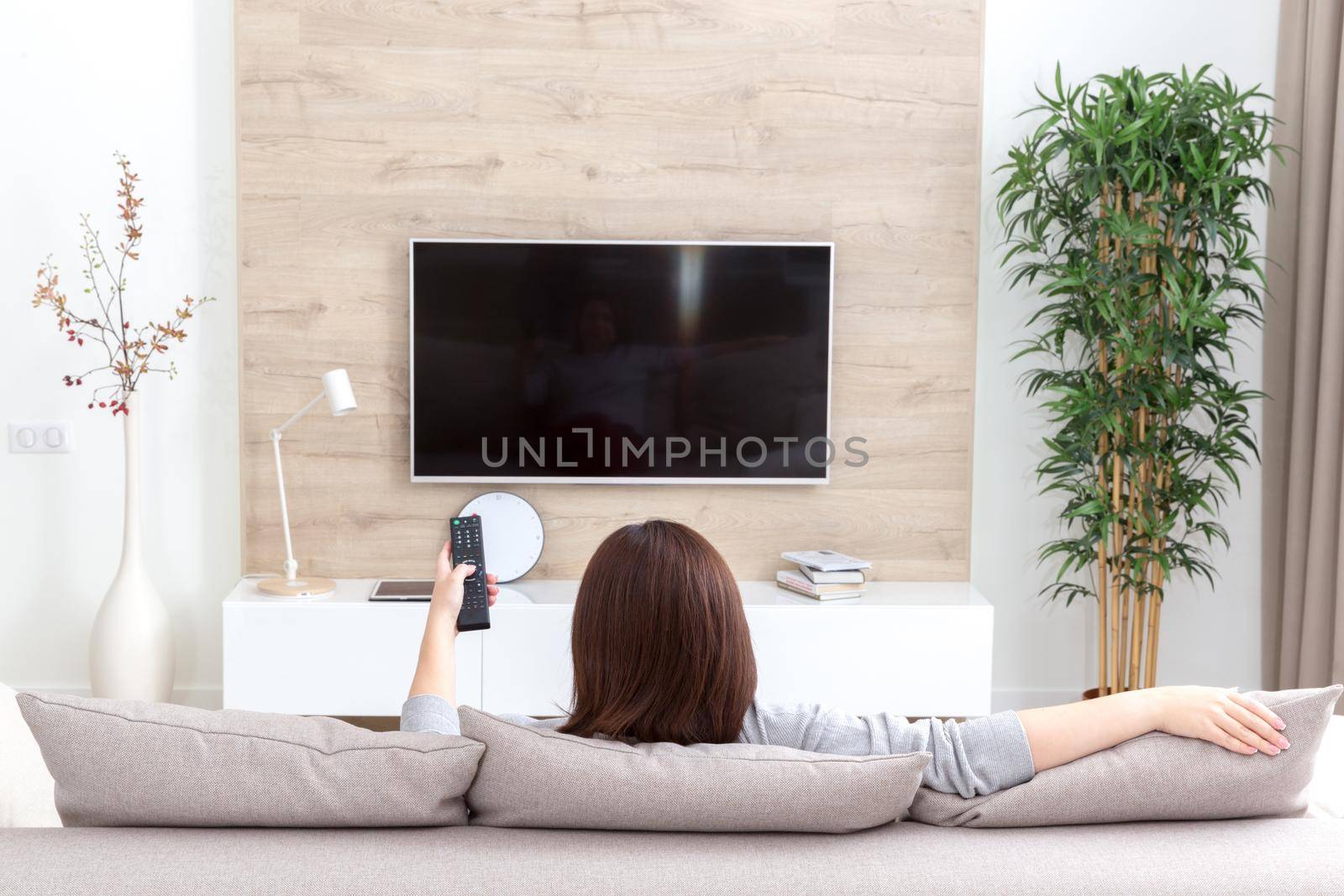 Young woman watching TV in the room by Mariakray