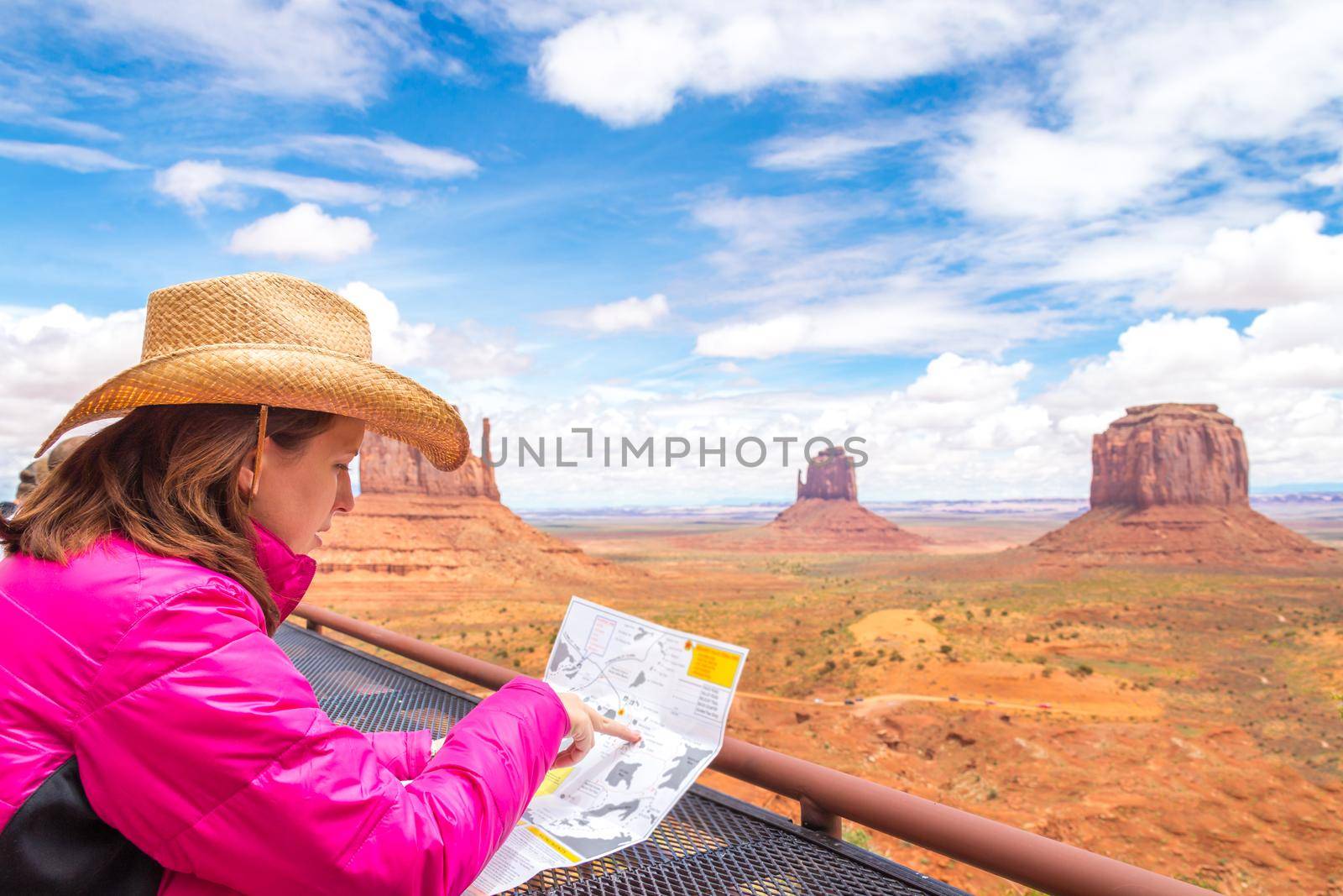 Woman sitting and looking at map in Monument Valley with red rocks overview in Arizona USA by Mariakray