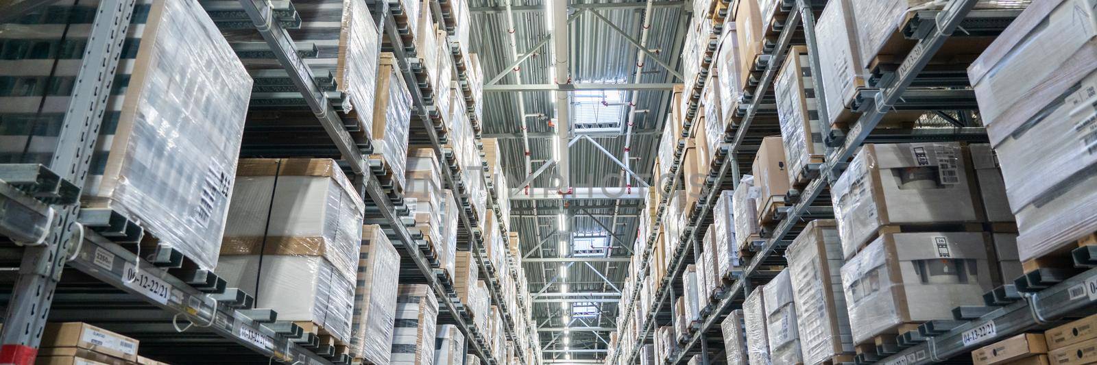 Panorama of Rows of shelves with boxes in modern warehouse by Mariakray