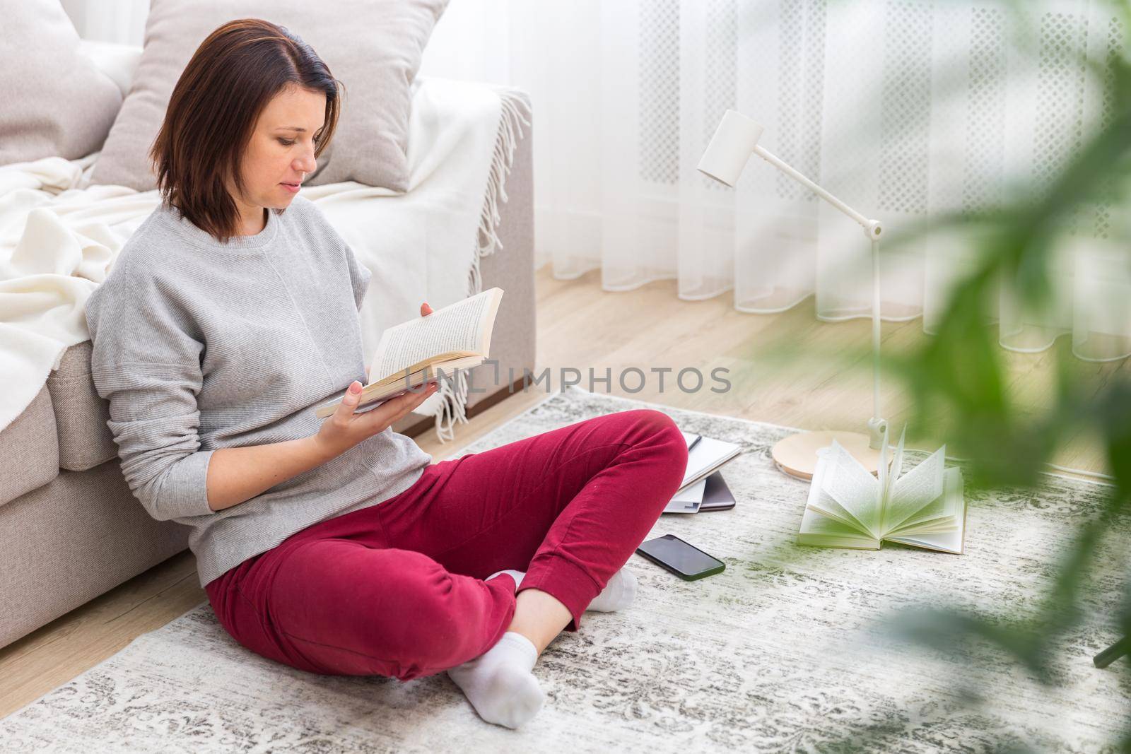 woman relaxing on floor at home reading book
