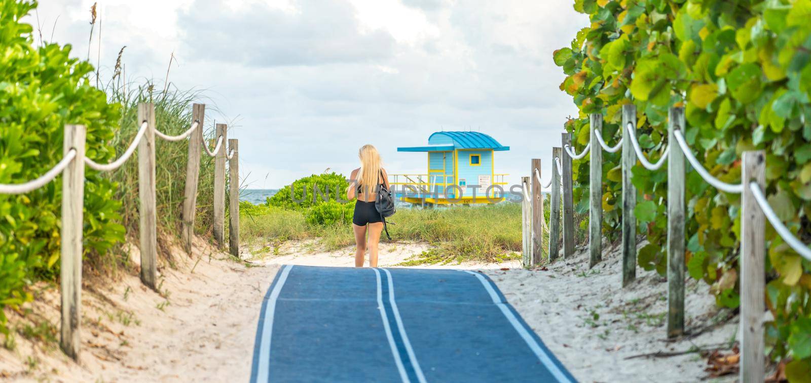 Woman walking to the beach on Footpath. South Beach in Miami, Florida, USA