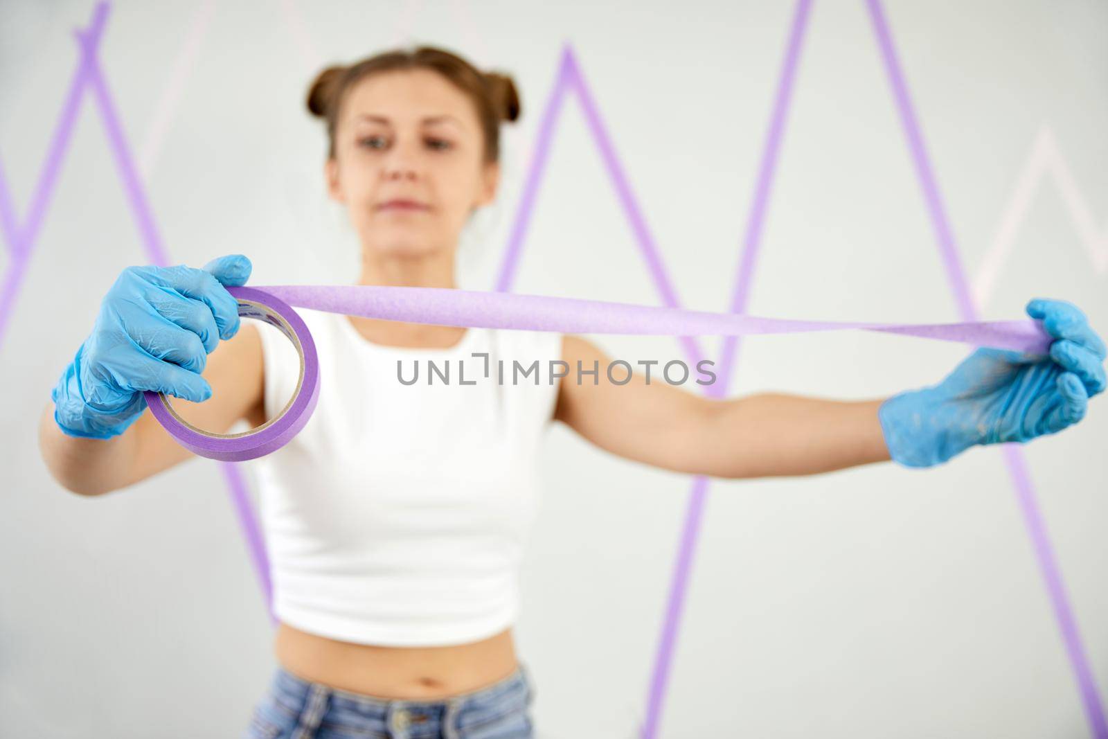 Young woman playing with masking tape before painting the walls