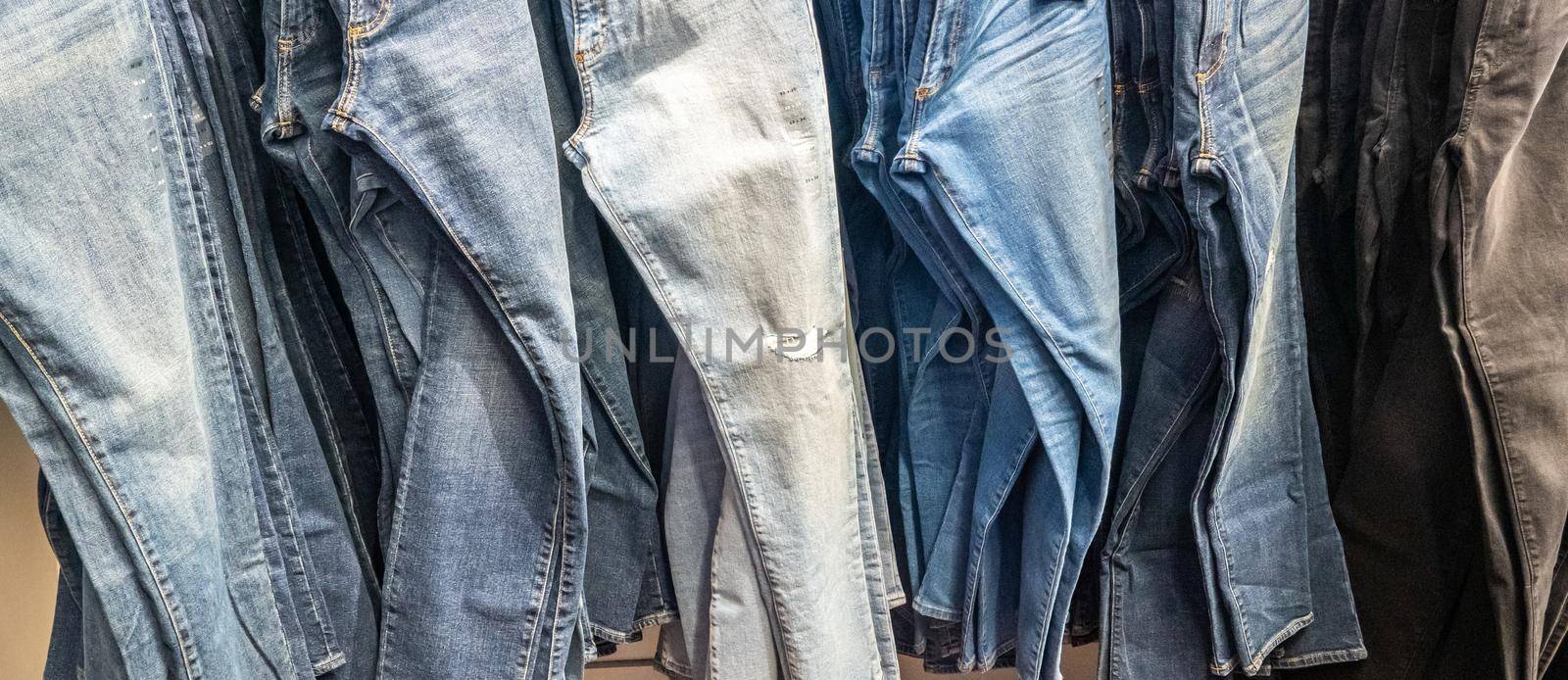 Jeans hanging on a rack. Row of denim pants.