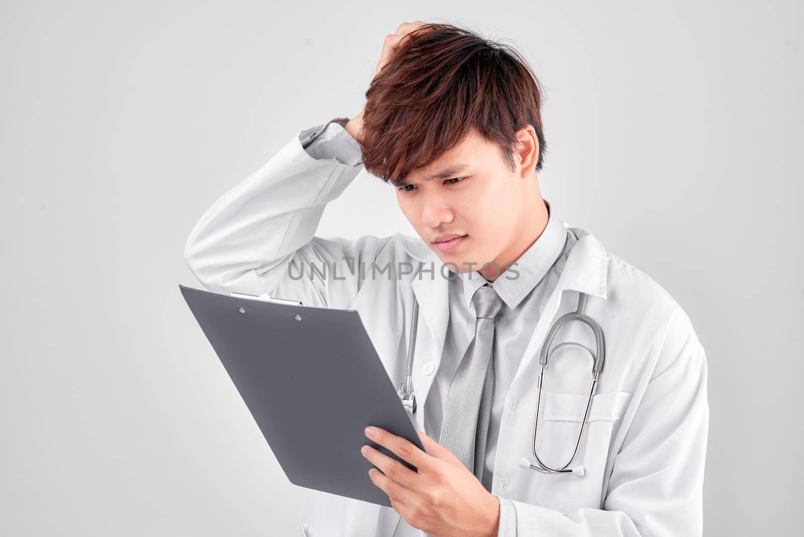 Studio shot of stressed man doctor holding clipboard by makidotvn