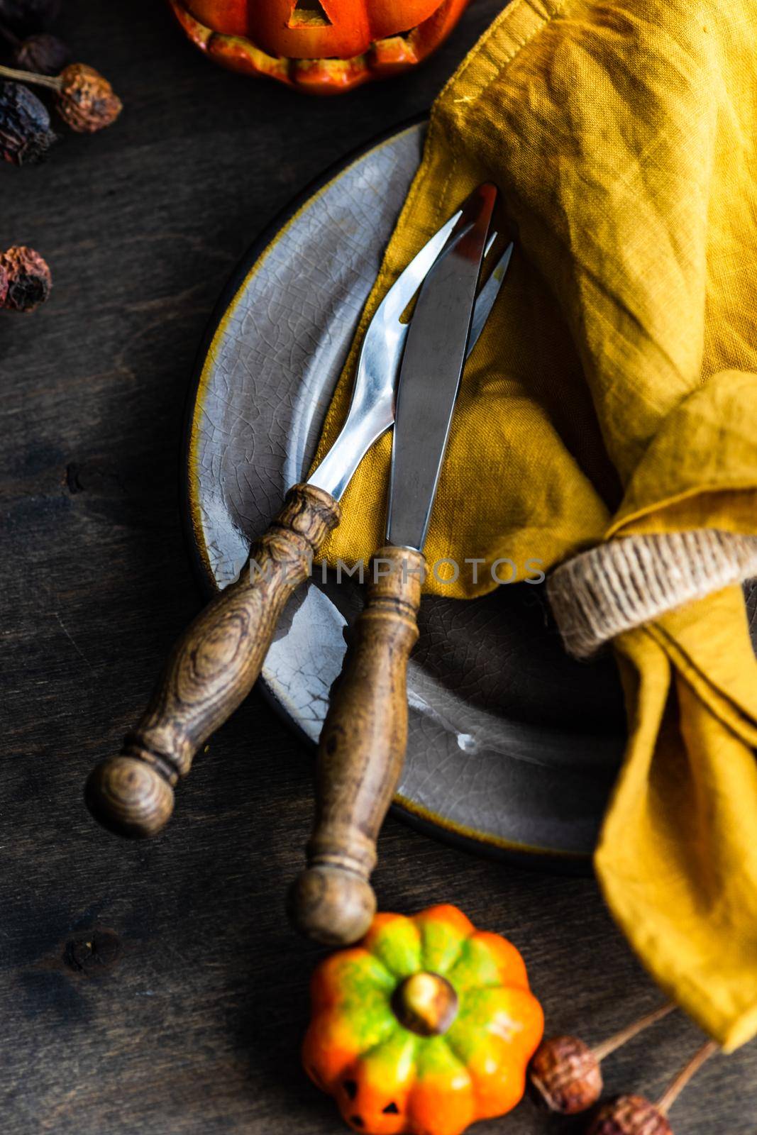 Thanksgiving holiday table setting with pumpkin and dried leaves