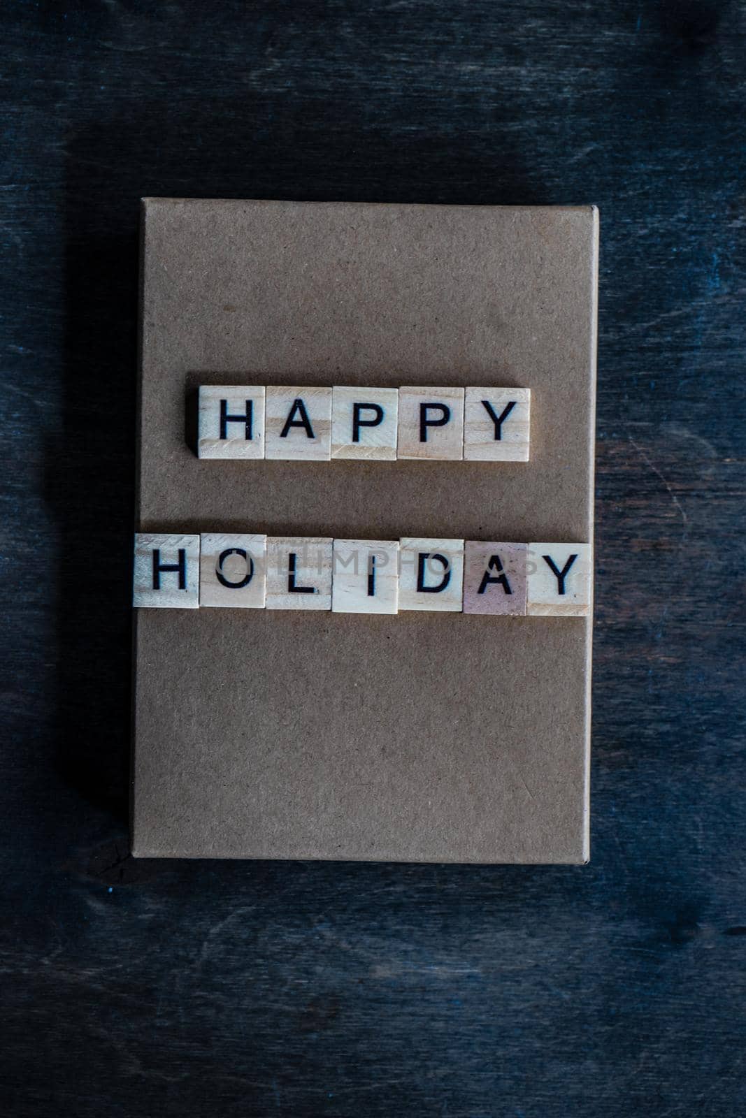 Holiday card concept with wooden blocks with letters on gift box on wooden background