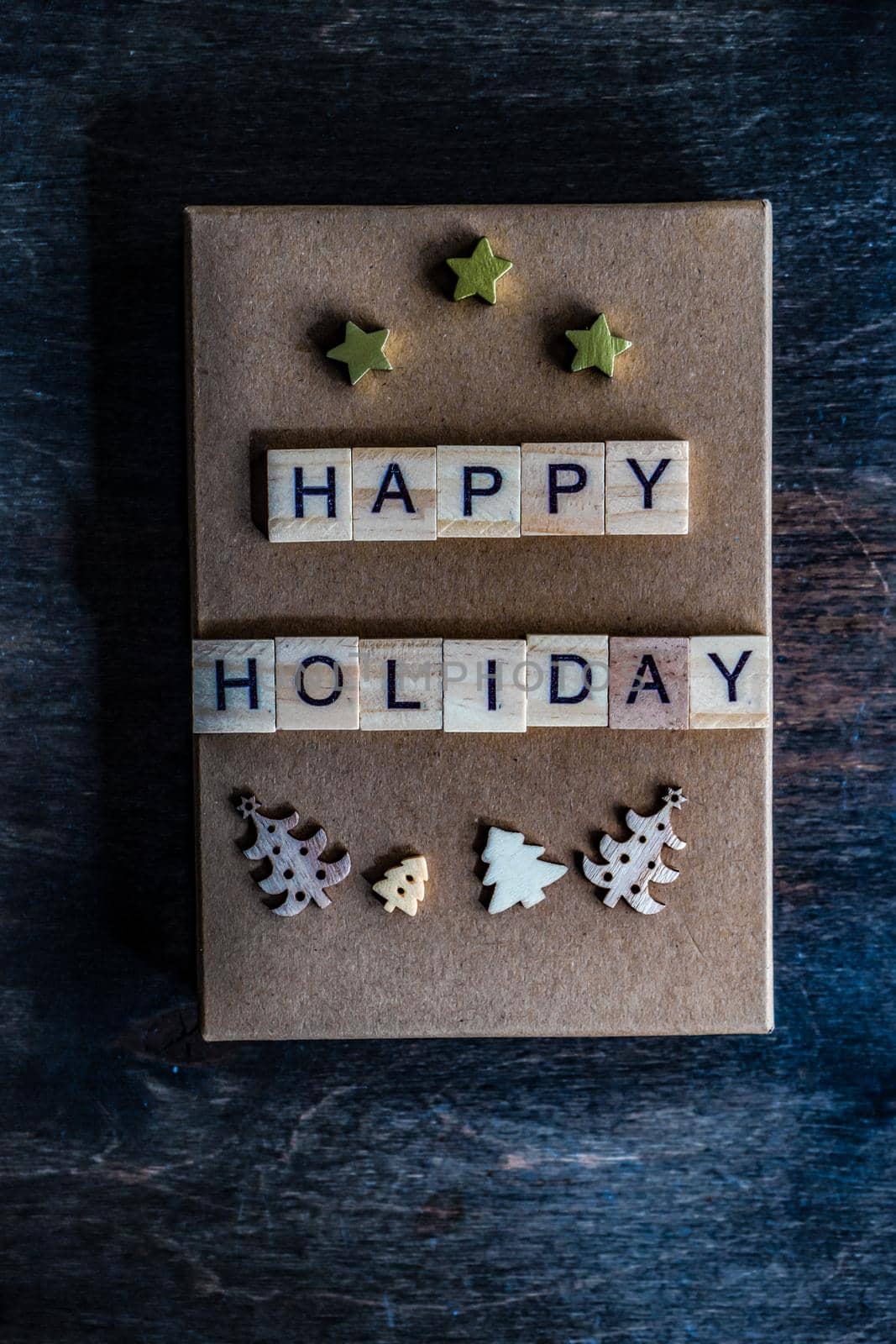 Holiday card concept with wooden blocks with letters on gift box on wooden background