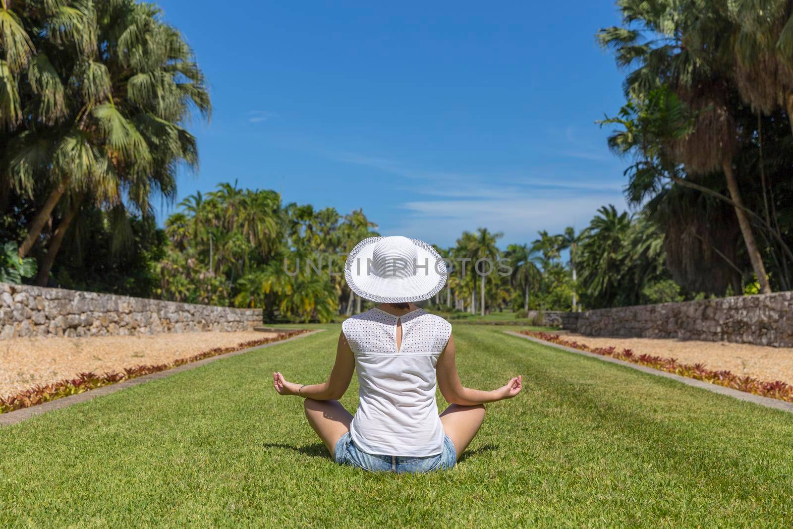 Woman doing yoga exercises in park sitting in lotus posture