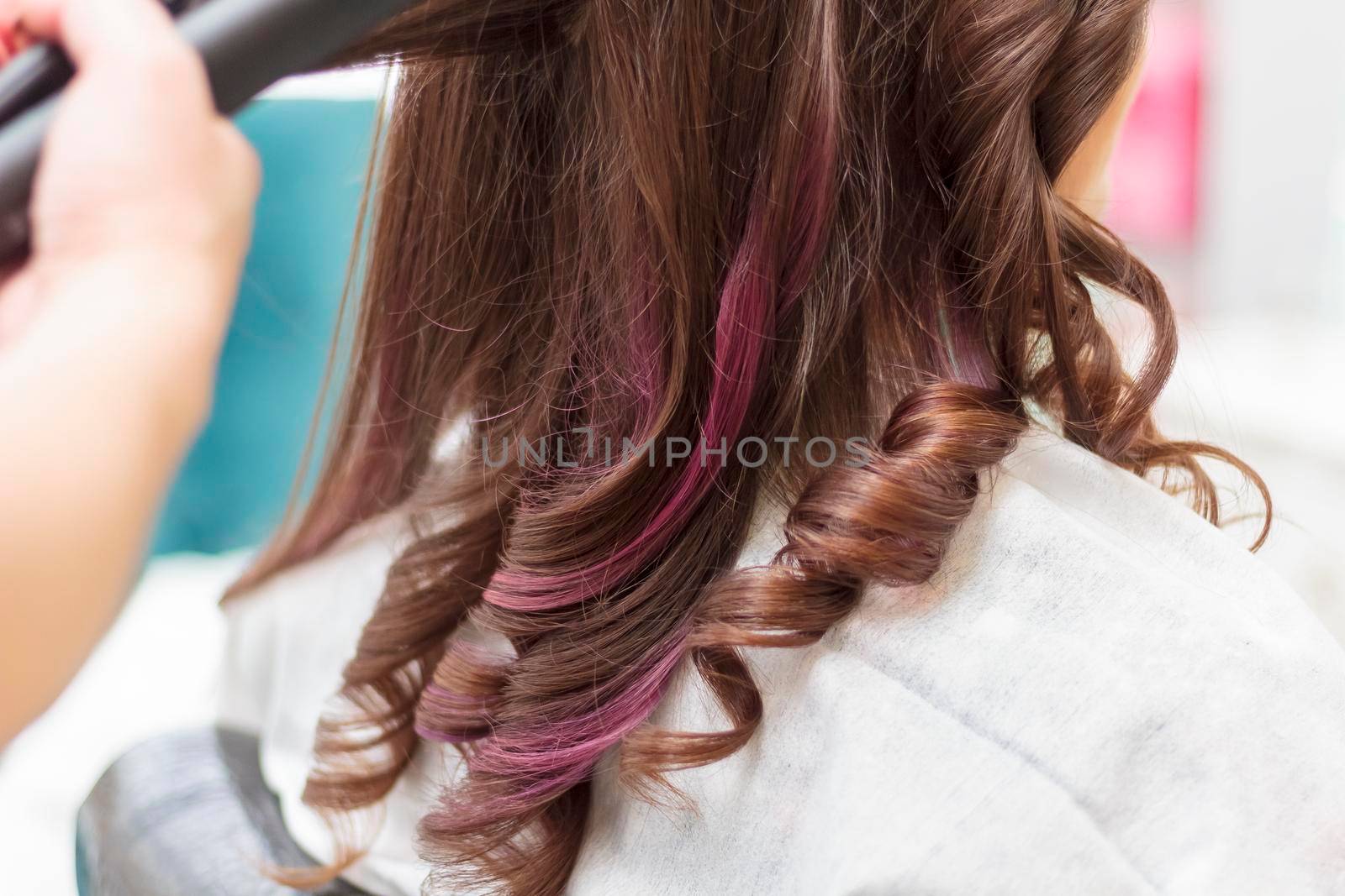 A master in a beauty salon curls curls for a girl with long hair. Close-up.