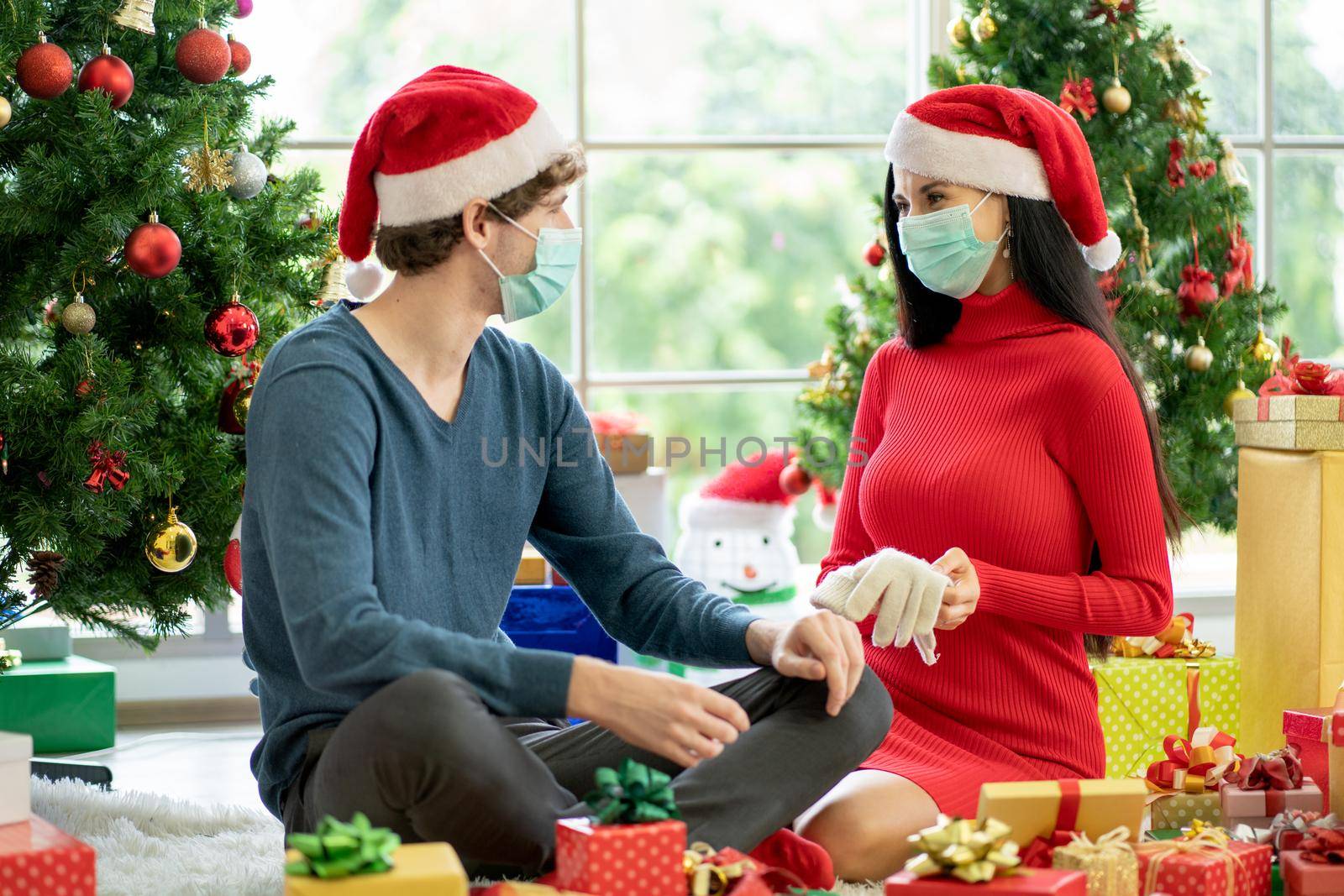 Woman with hygiene mask show gloves as the present to her lover with costume of Christmas festival during pandemic of Covid-19.