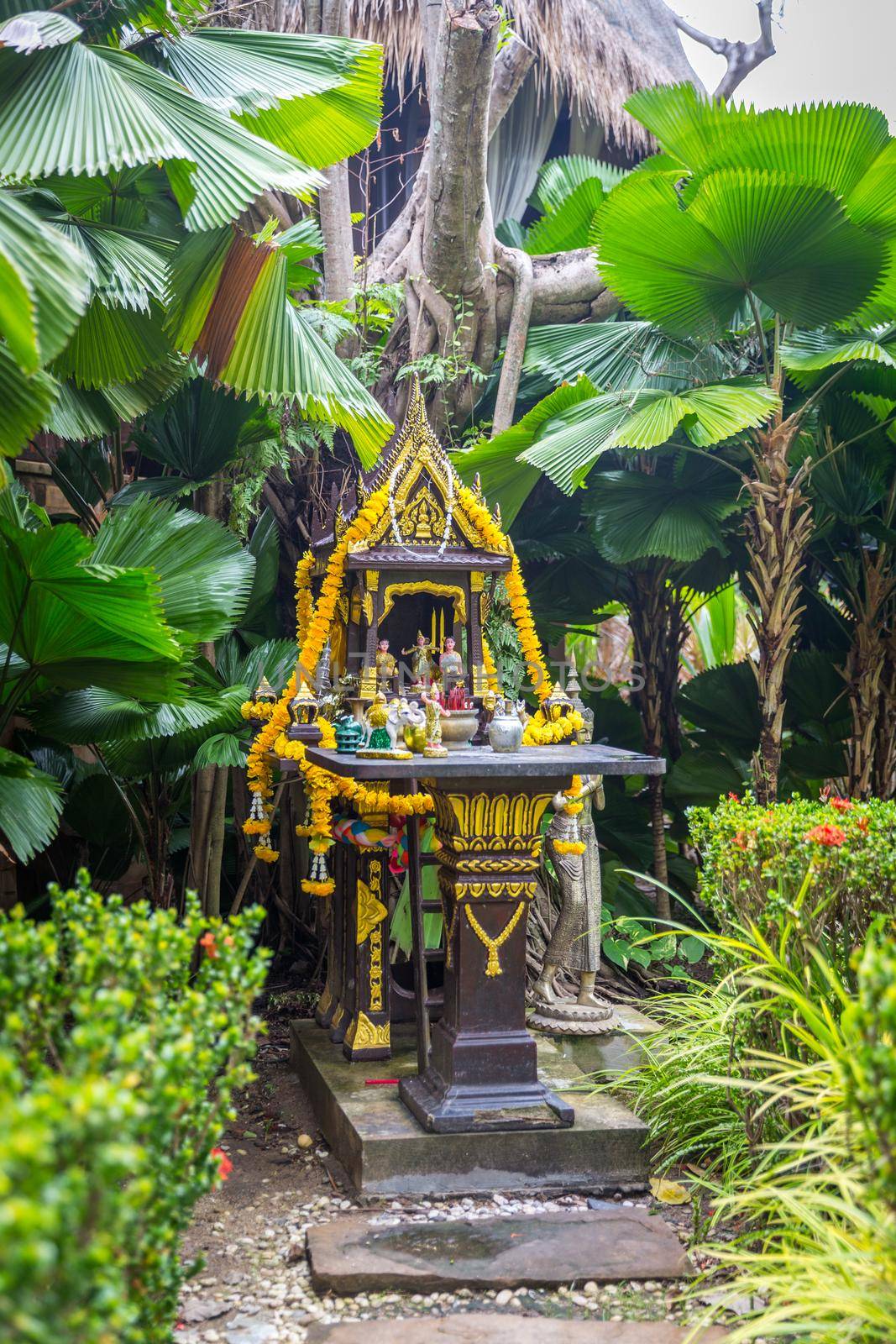 Traditional Thai spirit house with colorful garlands in Thailand