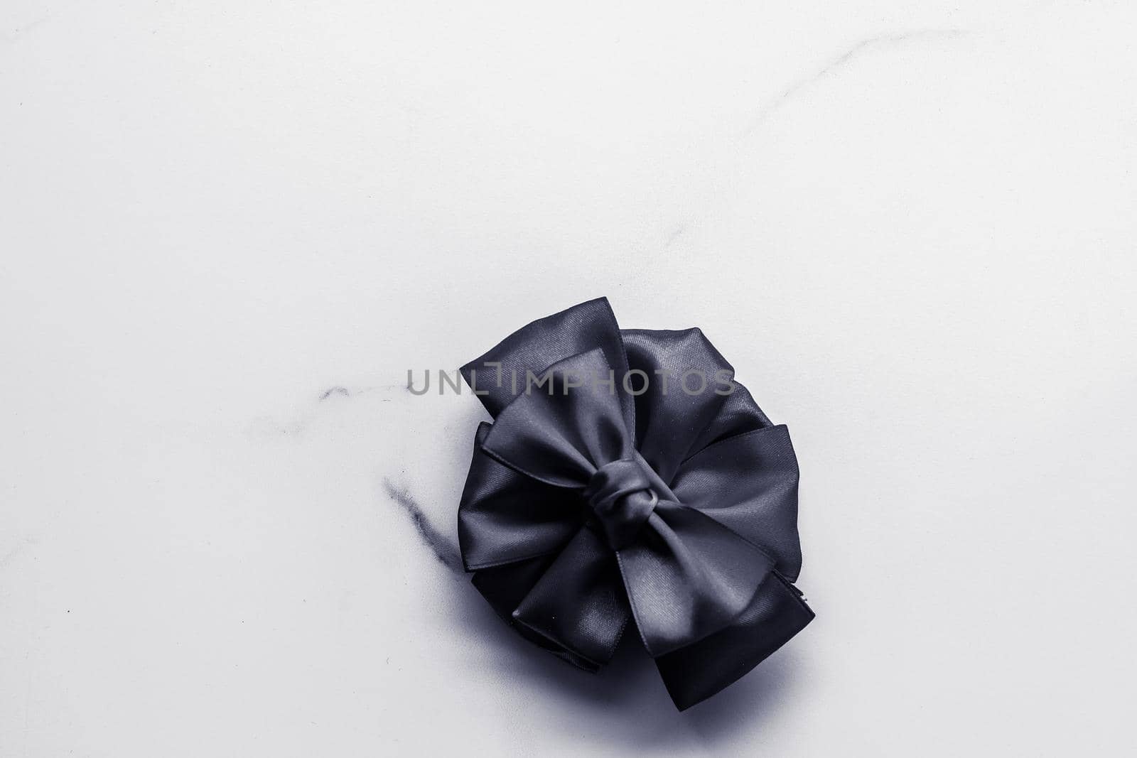 Black silk ribbon and bow on marble background, flatlay by Anneleven