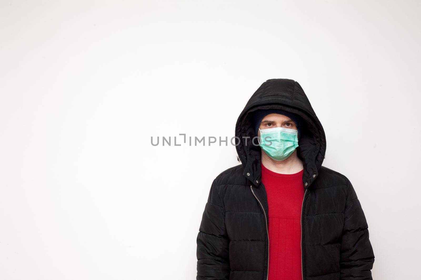 Man with green protective mask on white background. A man with a red sweater and a black jacket.