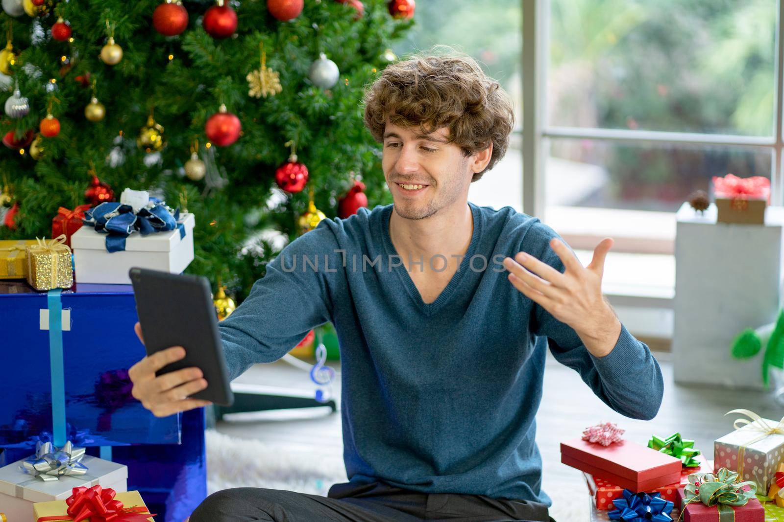 Caucasian man show greeting action to other people look like his friend or family during Christmas holiday festival and sit with several decoration things.