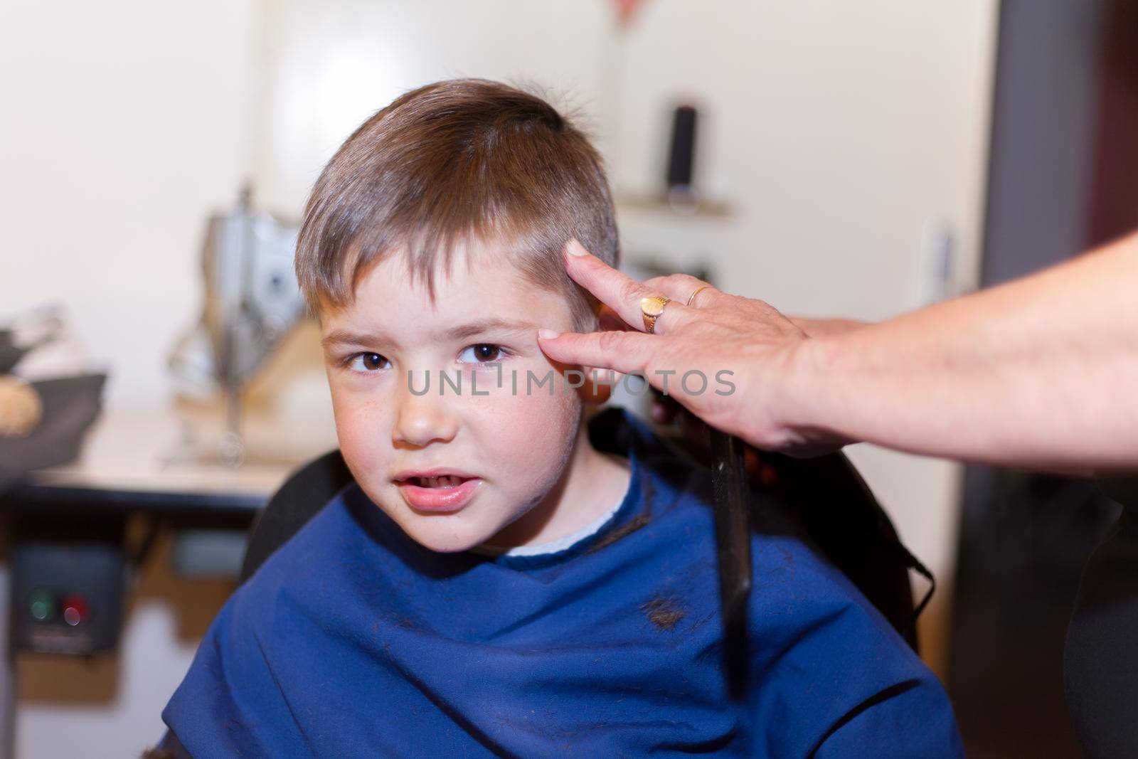 Boy is having a home haircut in home maide sewing room. living at home during lockdown.