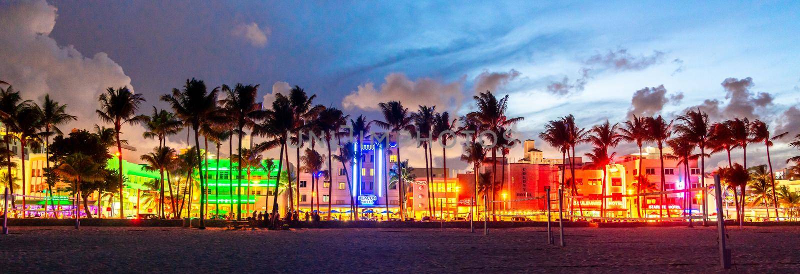 Miami Beach, USA - September 10, 2019: Panorama of Ocean Drive hotels and restaurants at sunset. City skyline with palm trees at night. Art deco nightlife on South beach by Mariakray