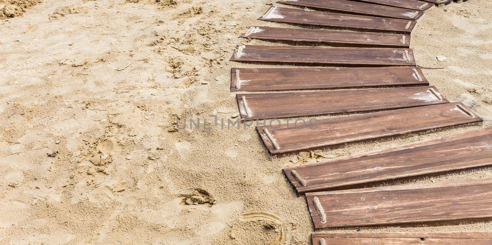 Wooden beach boardwalk, path with sand with copy space