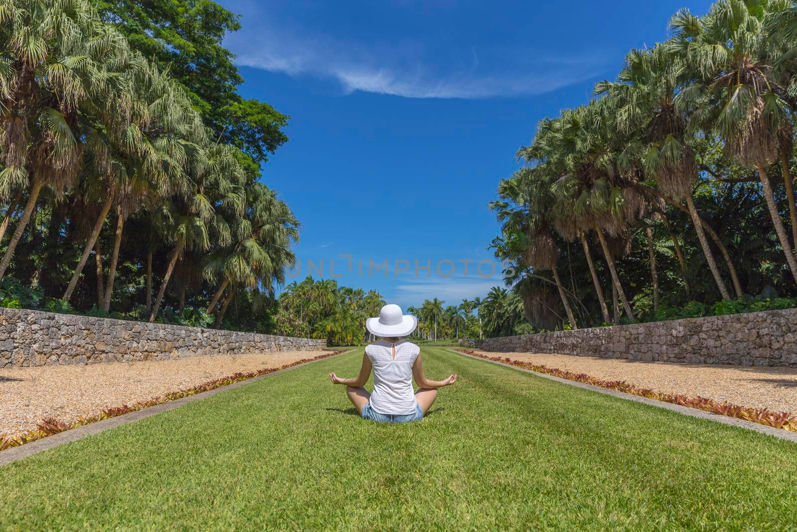 Woman doing yoga exercises in park sitting in lotus posture