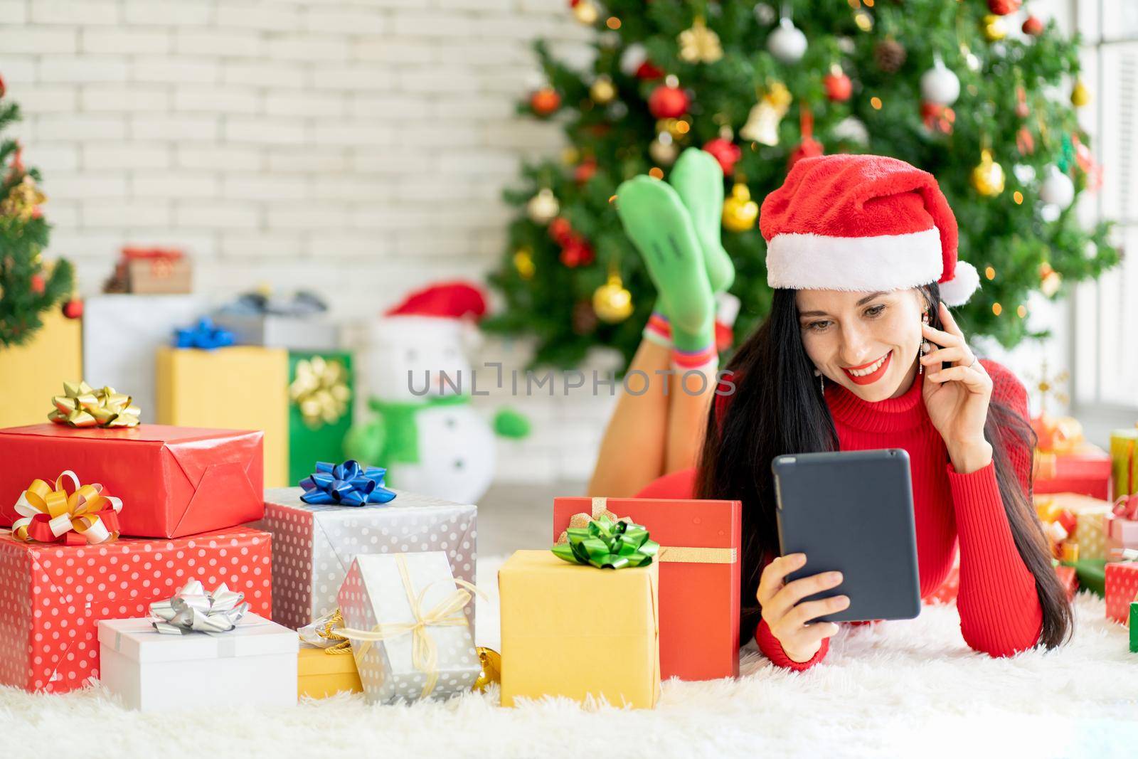 Pretty woman with Christmas costume hold tablet and smile with happiness during Christmas festival. by nrradmin