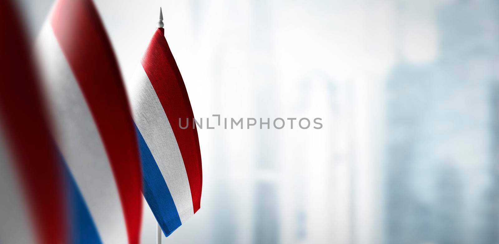 Small flags of Netherlands on a blurry background of the city.